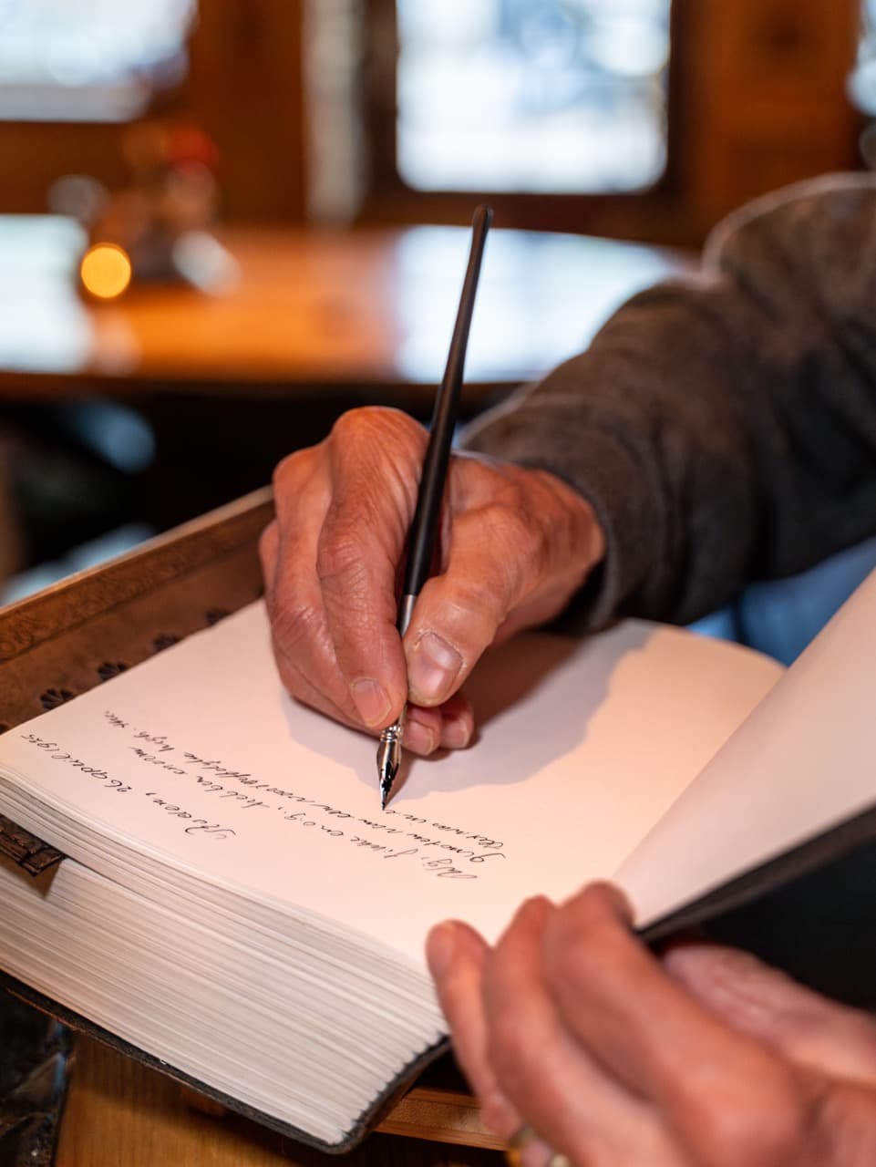 Gast schrijft met een vulpen een bericht in het gastenboek van Onder de Linden