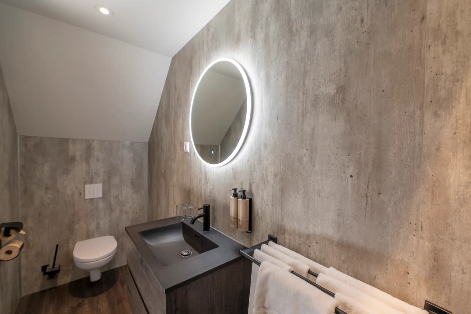 Badkamer in betonlook met een ronde verlichte spiegel