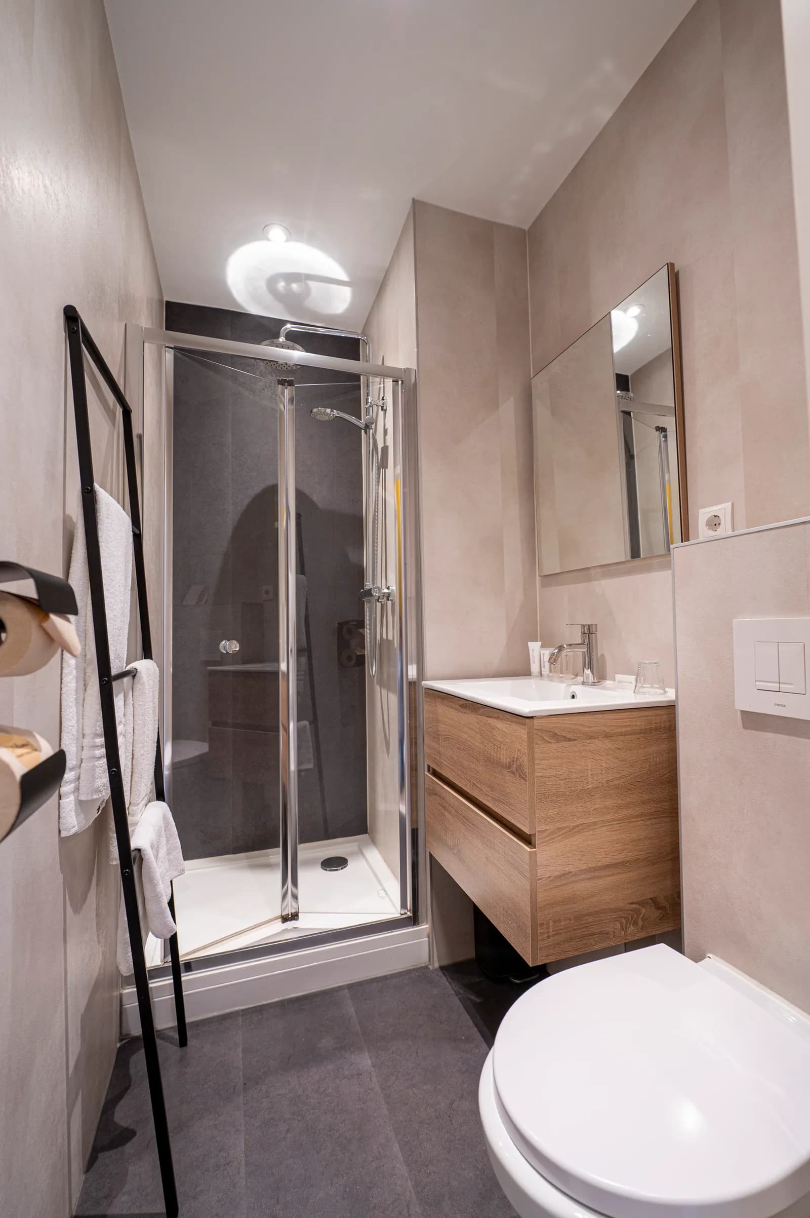 Badkamer met douchecabine, wastafel en handdoekenrek