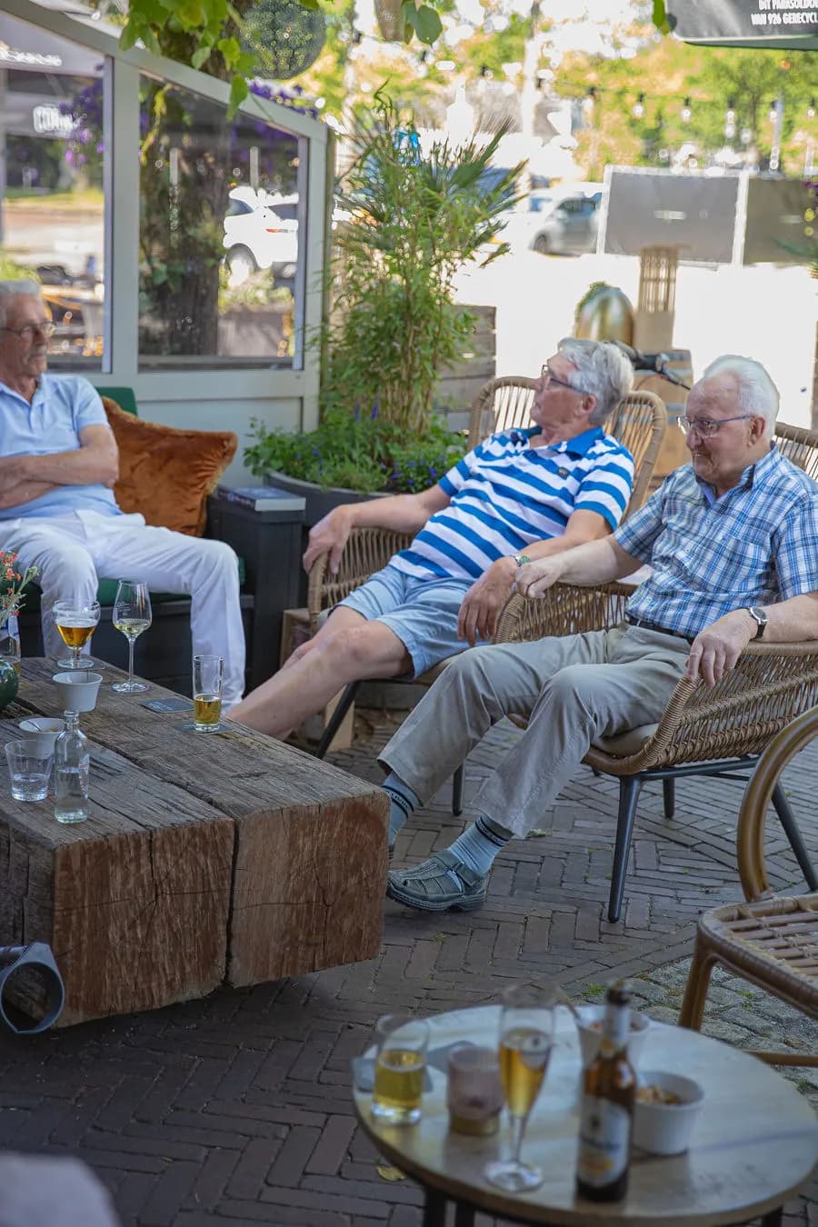 Heren met speciaalbier in loungestoelen op het terras