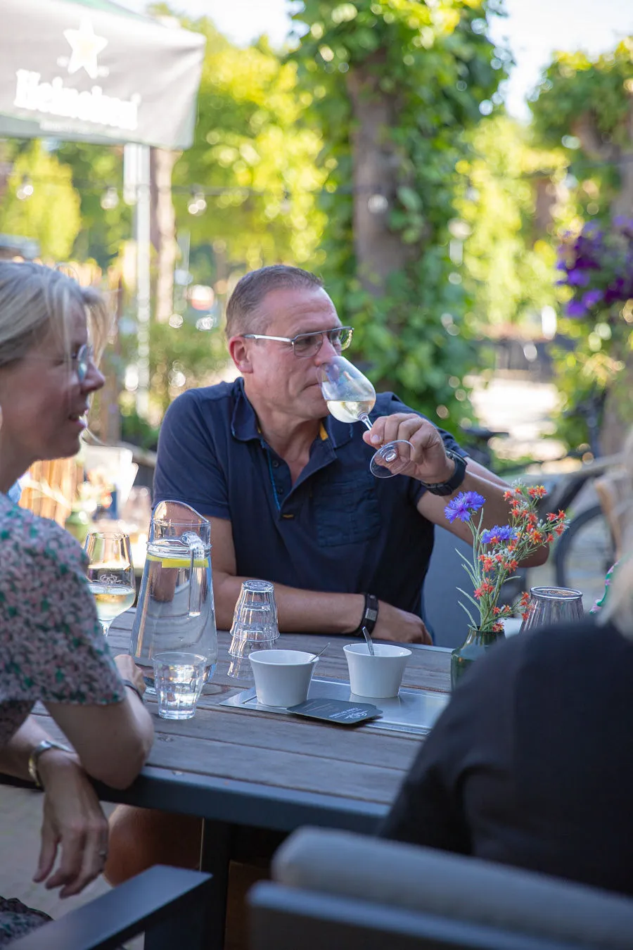 Gast proeft een glas witte wijn aan een terrastafel