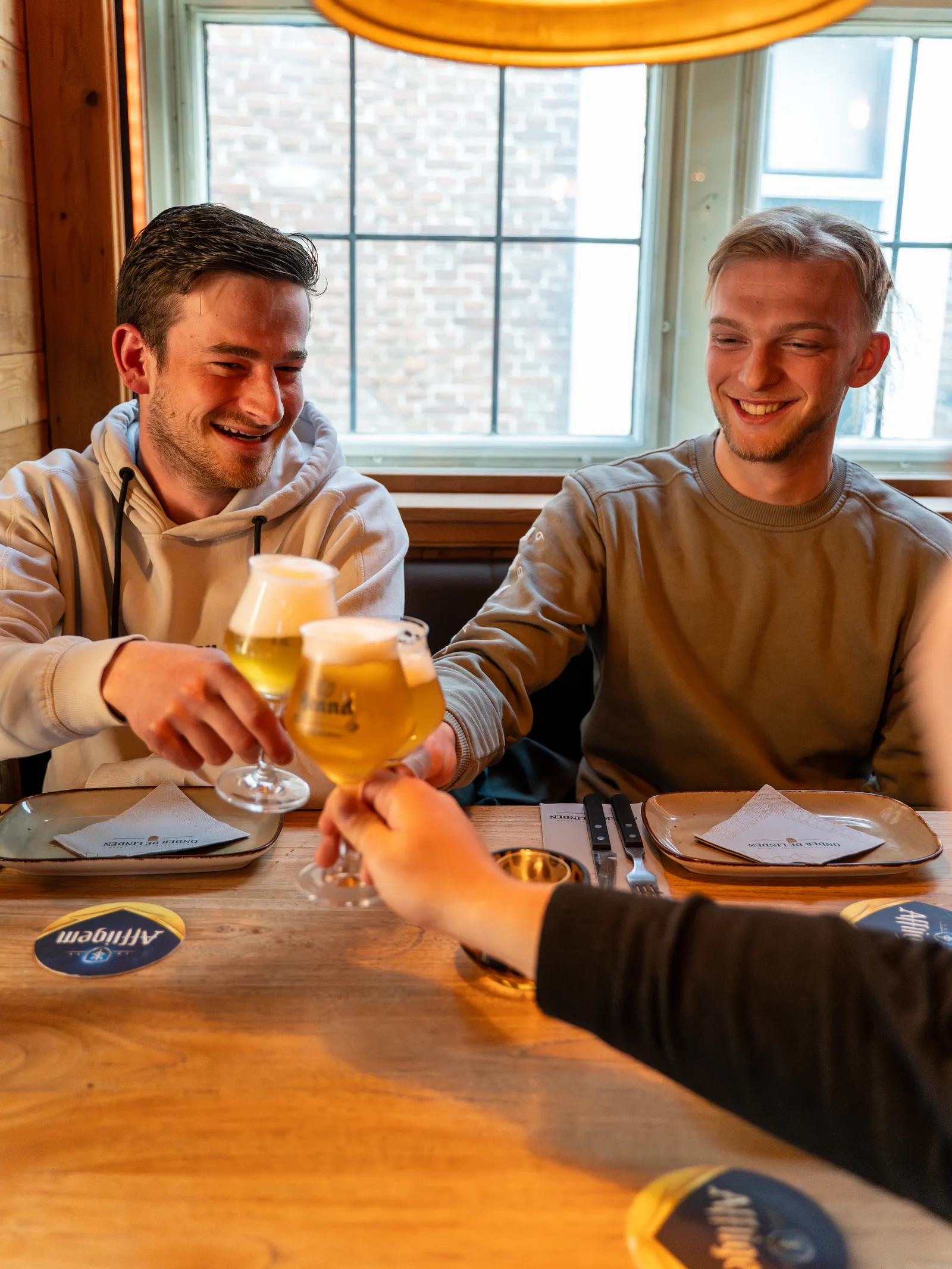Twee mannen proosten met speciaalbier aan tafel in Roden