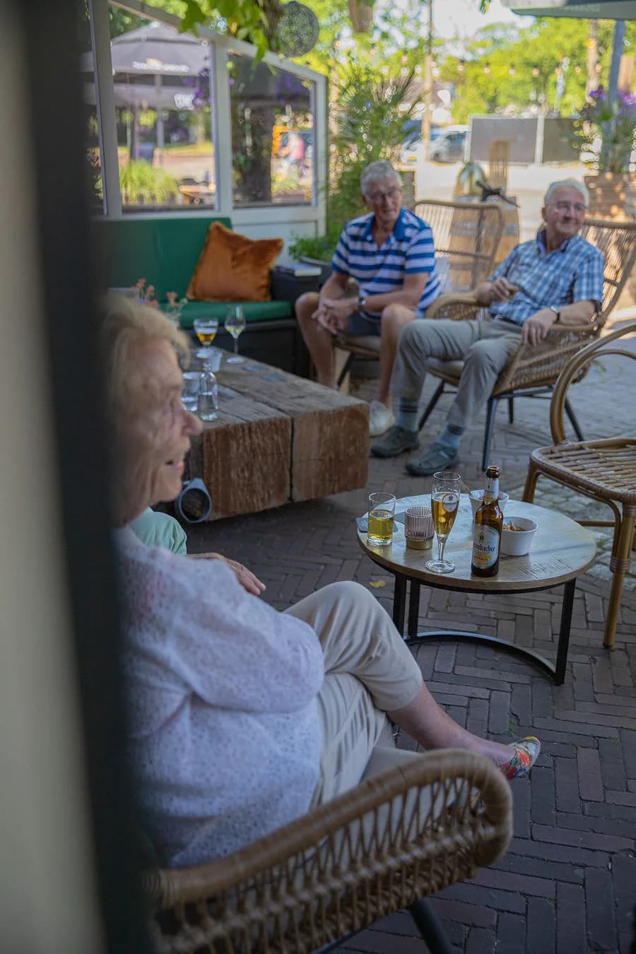 Gasten borrelen met bier en bubbels op het overdekte terras