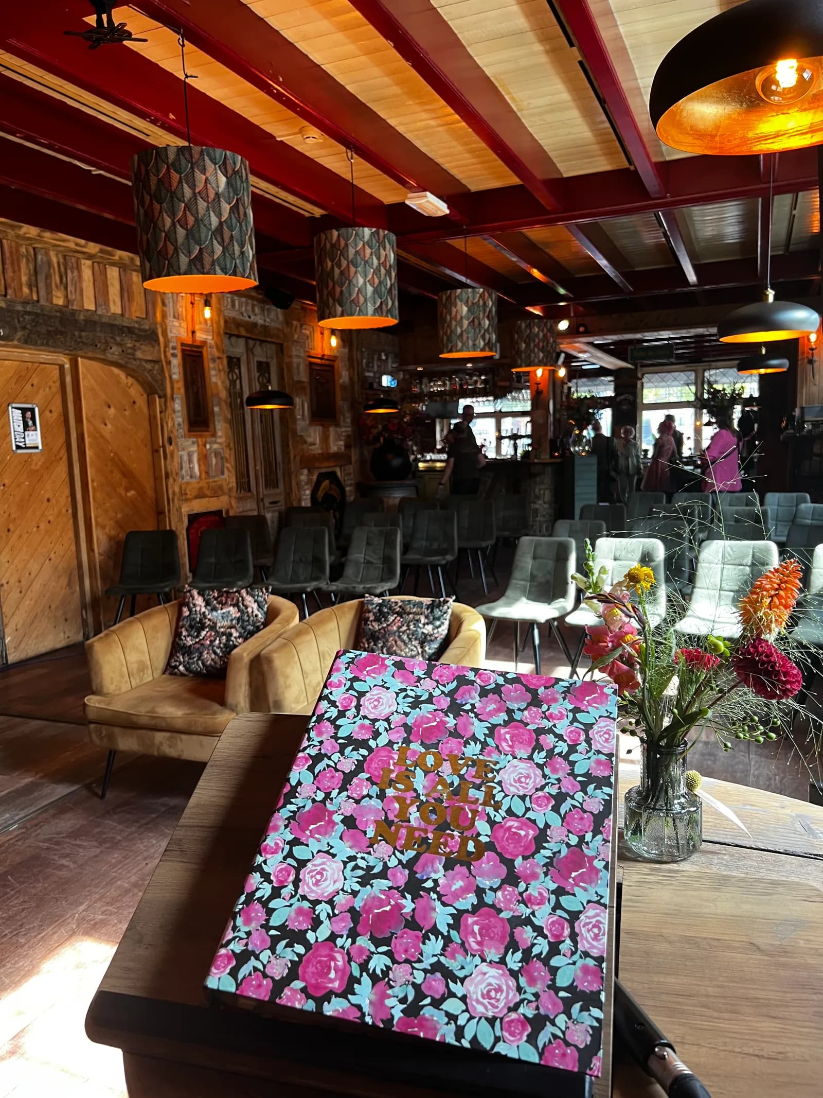 Boek met bloemenkaft op tafel, met de fauteuils en de opgestelde stoelen erachter