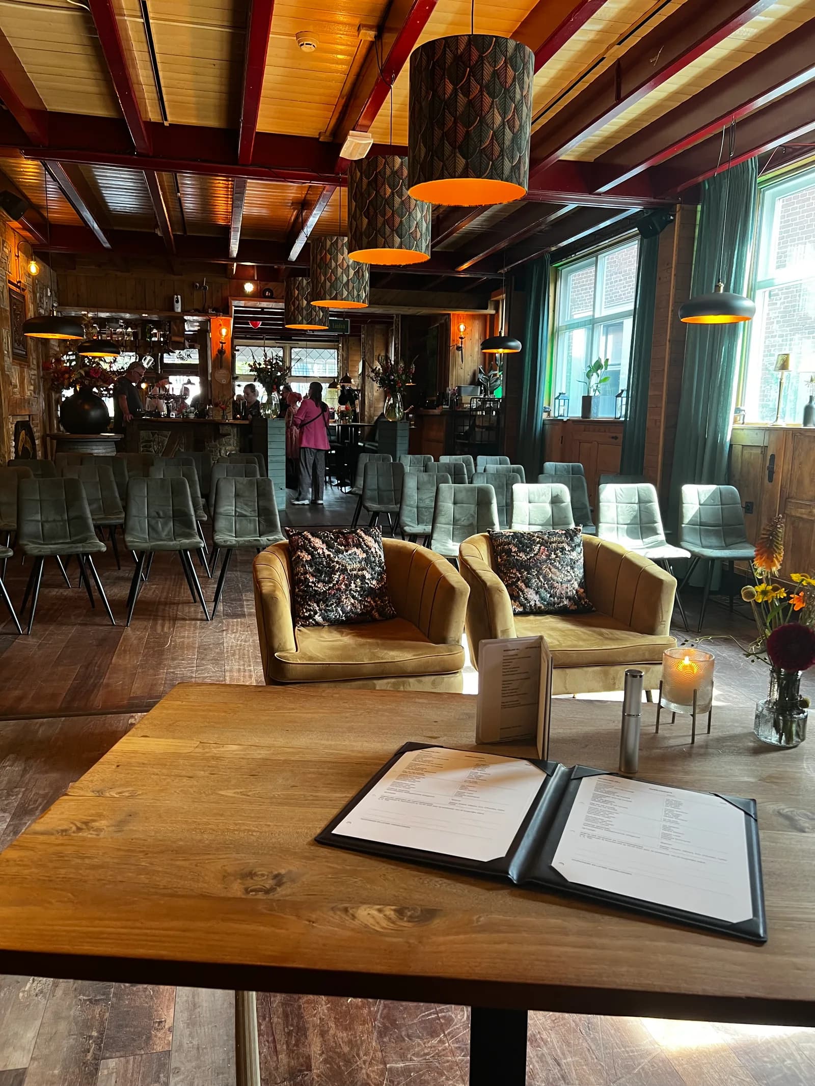 Twee okergele fauteuils en de opgestelde stoelen, met een menukaart op de tafel ervoor