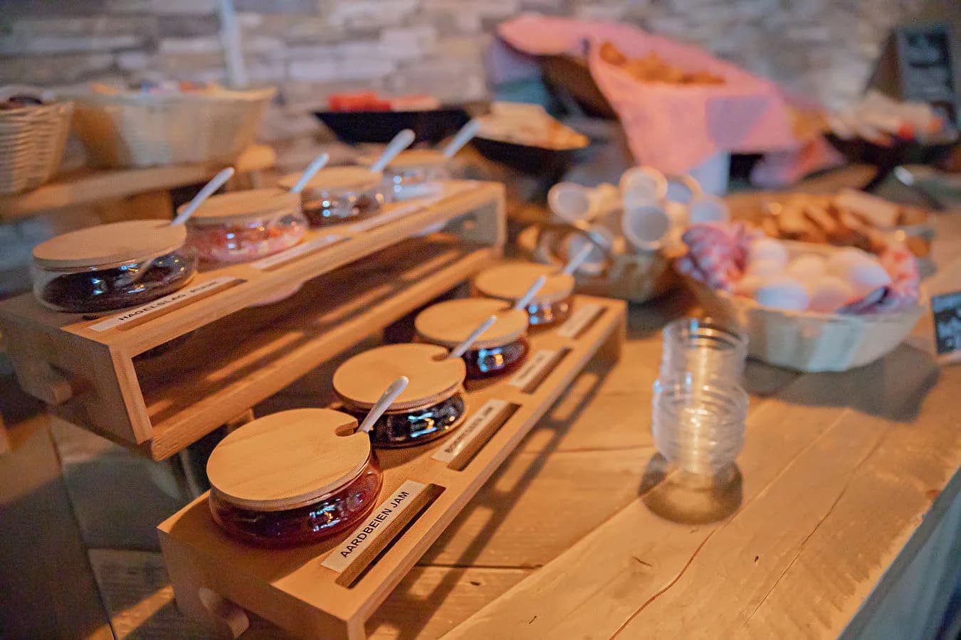Navulbare potten jam en hagelslag met houten deksels in een rekje op het buffet