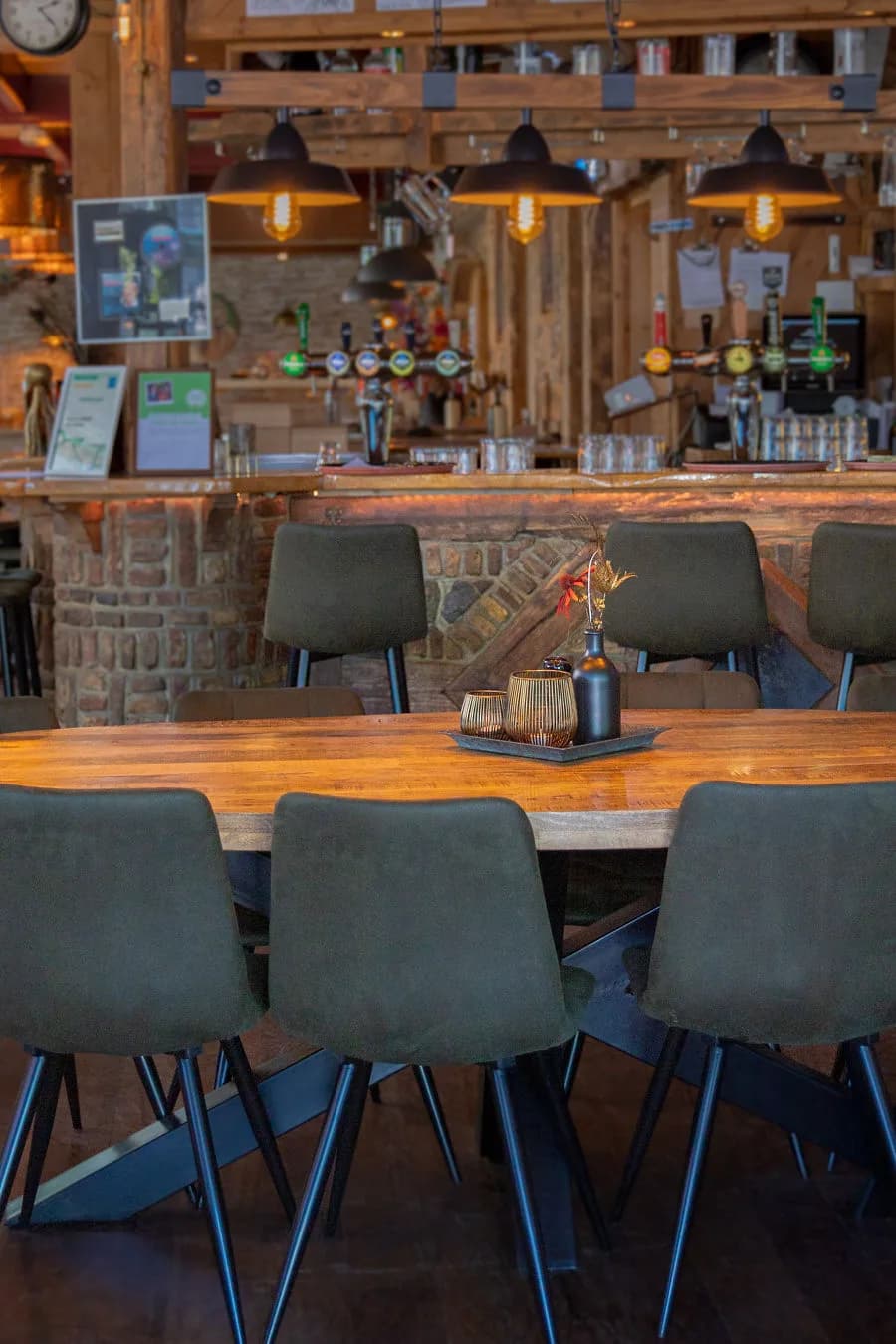 Eettafel met grijze stoelen en de bar met biertaps op de achtergrond