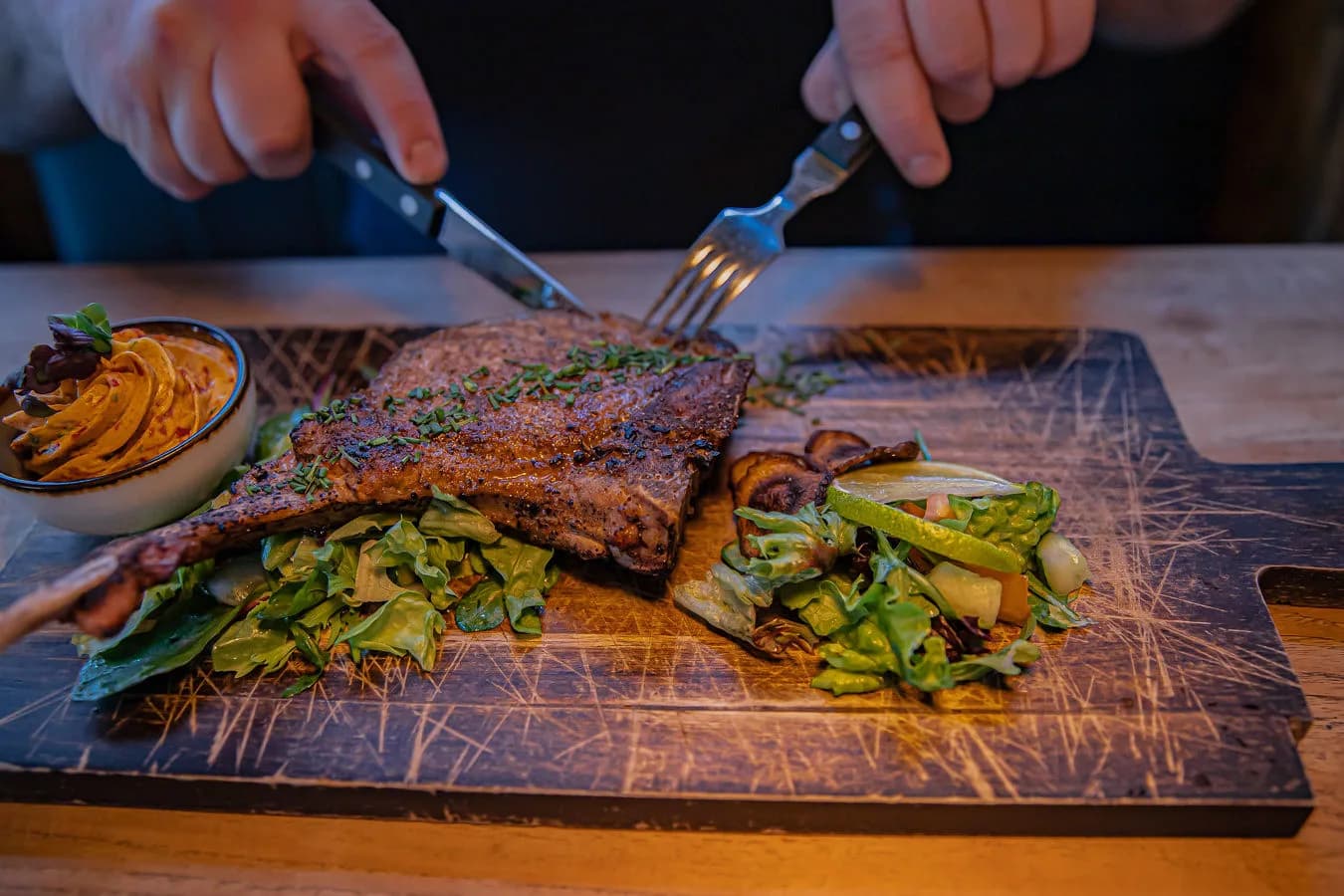Gegrilde cote wordt aangesneden op een houten plank