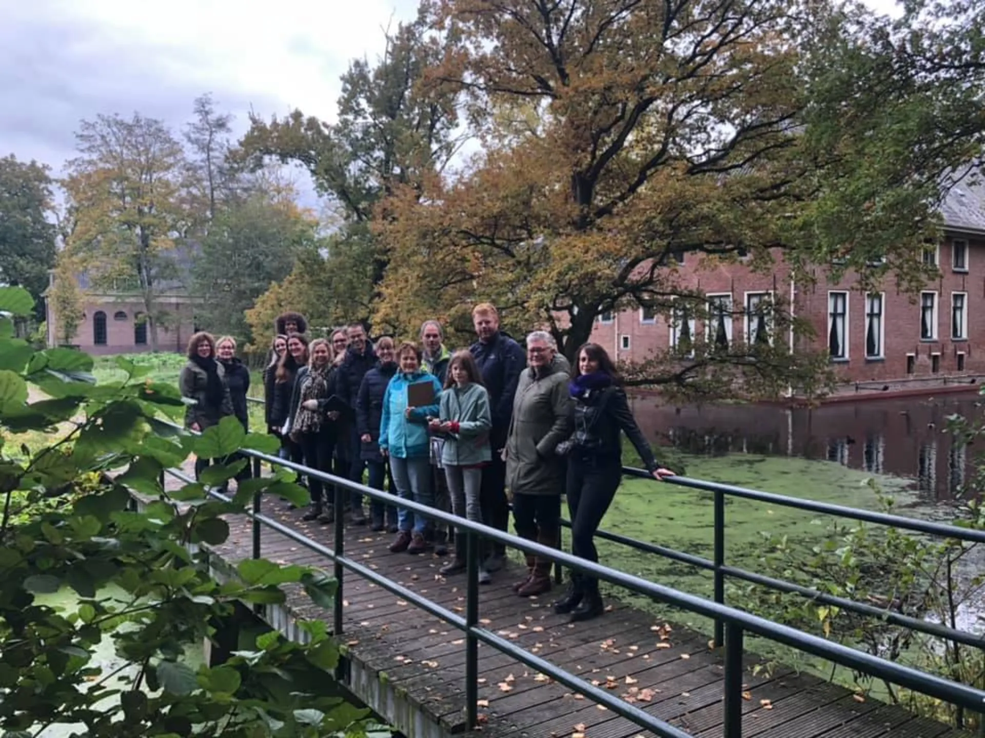 Groep op een houten brug bij een borg met gracht in de herfst