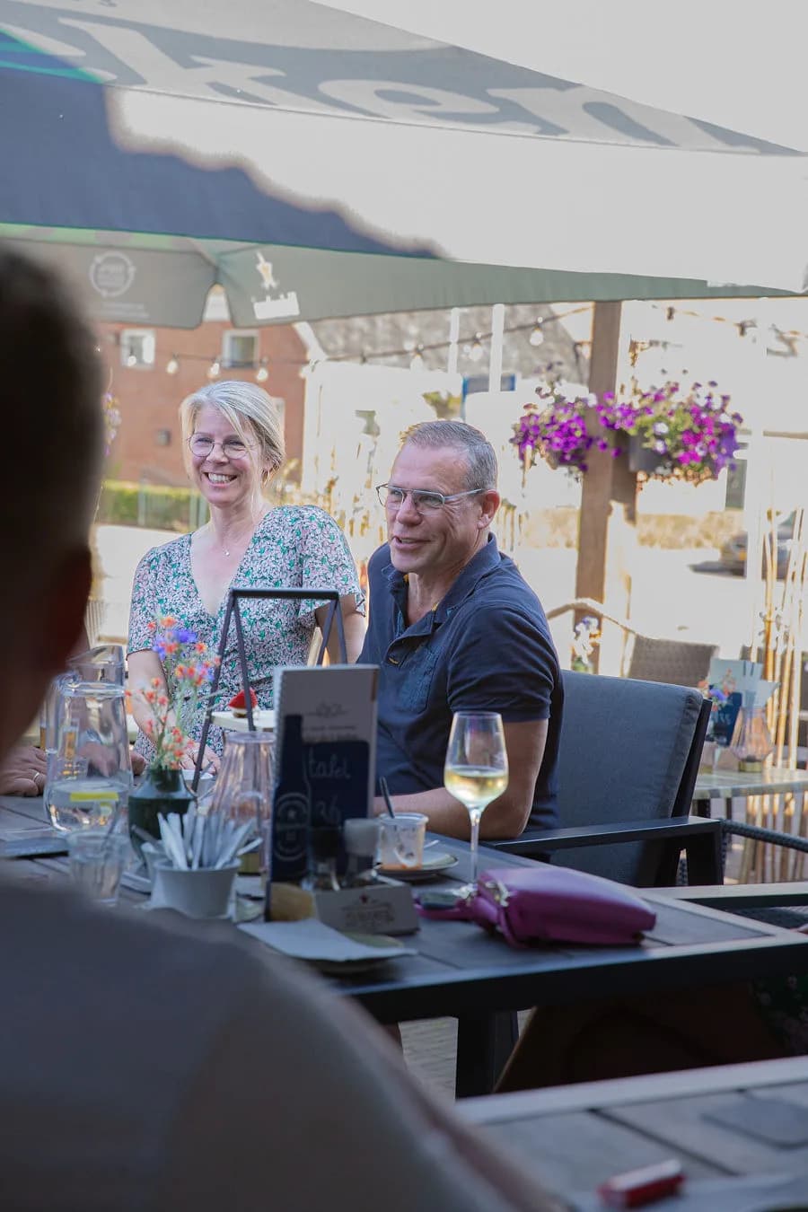 Stel aan een gedekte terrastafel met wijn onder de parasol