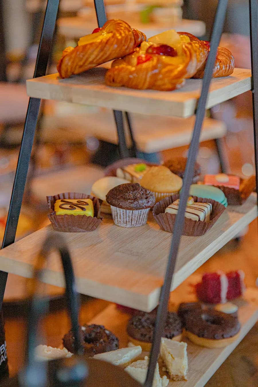 Etagère met croissants, petitfours, cakejes en donuts op houten plateaus