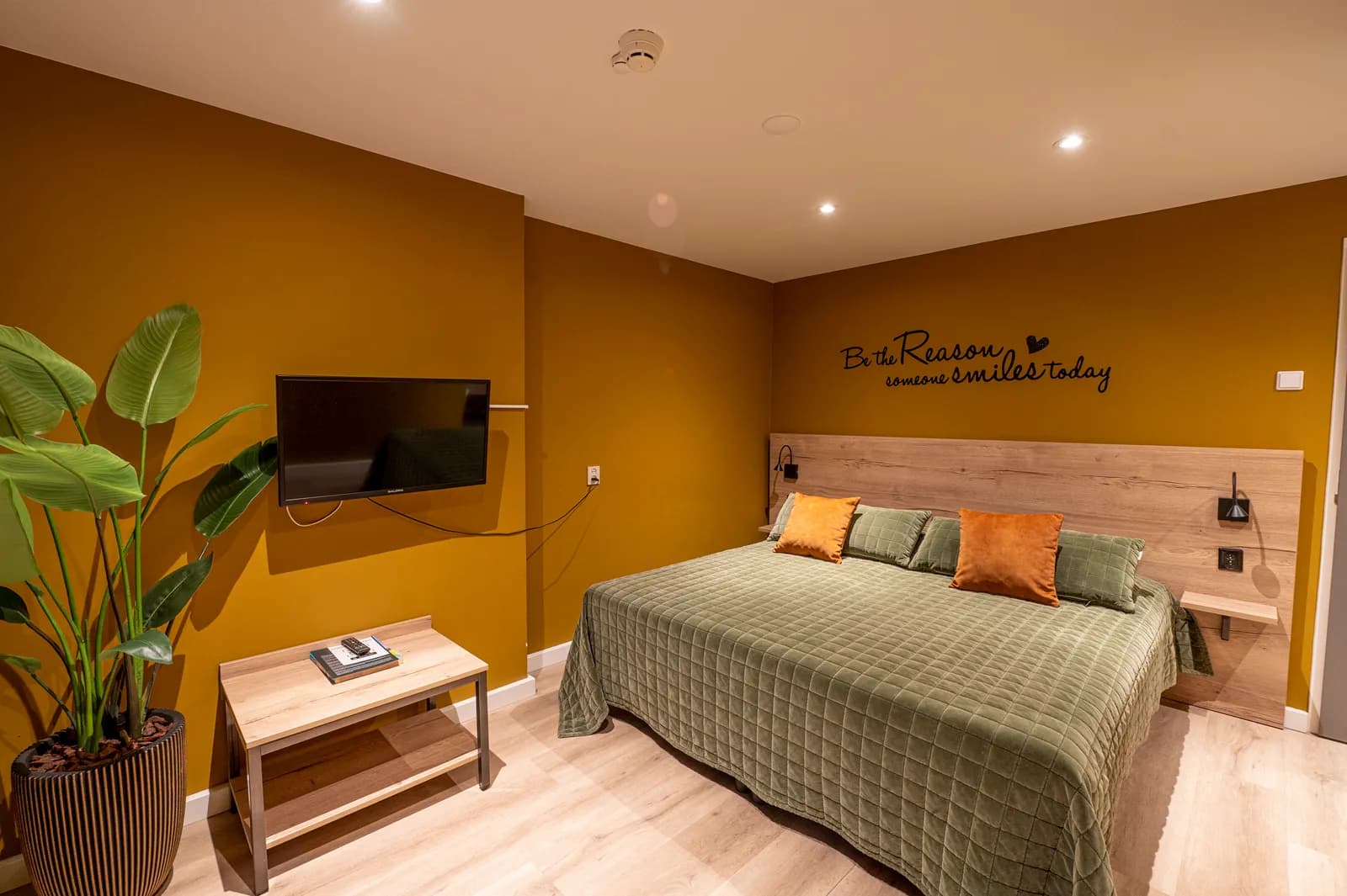 Comfort plus kamer met tv-wand en de muurtekst Be the reason someone smiles today