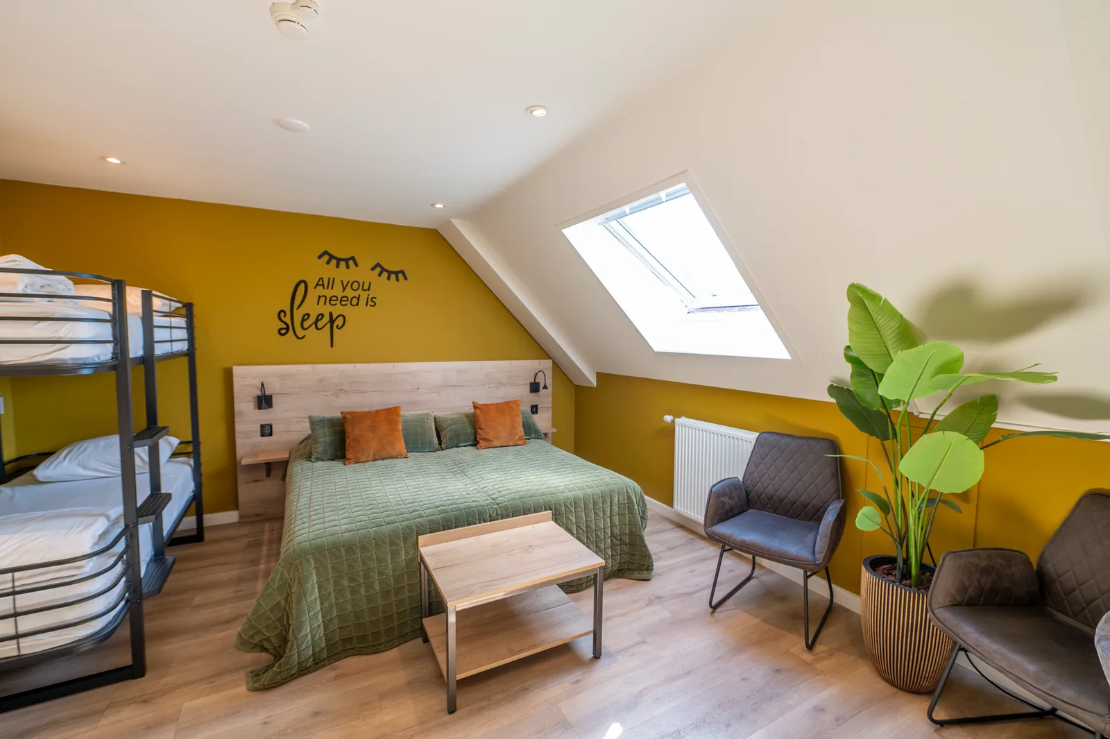 Ruime kamer met stapelbed, tweepersoonsbed en een zithoek onder het dakraam