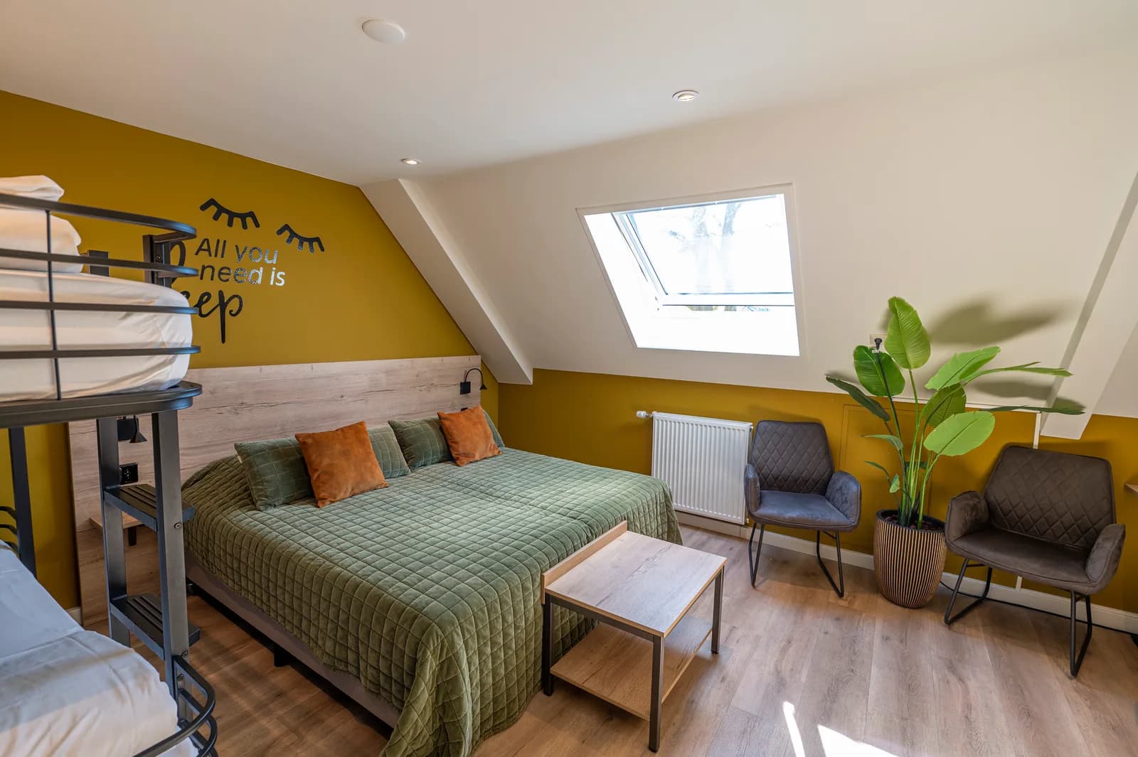 Familiekamer met stapelbed, tweepersoonsbed onder het dakraam en twee fauteuils