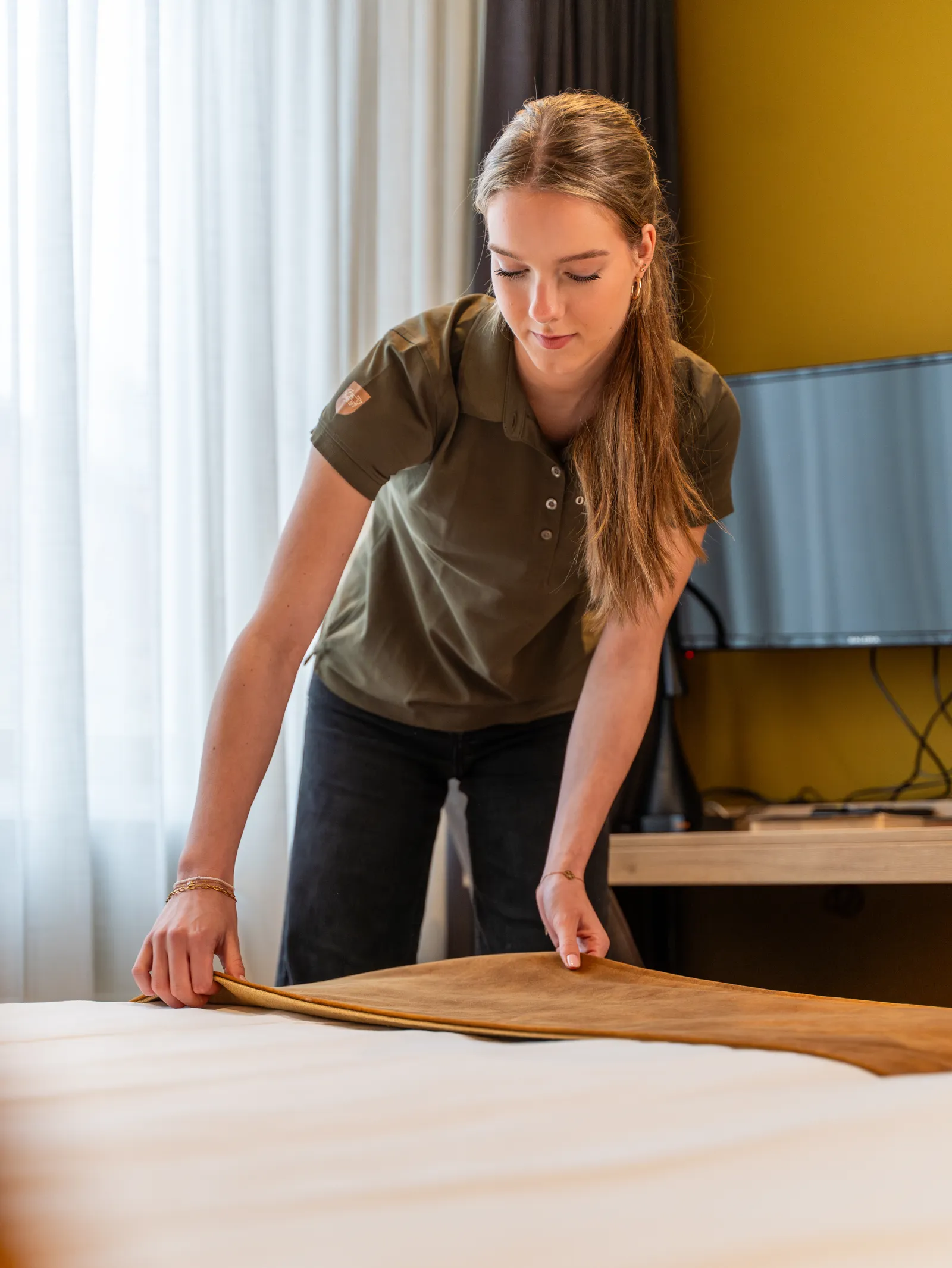 Medewerkster legt de bedloper recht in een hotelkamer