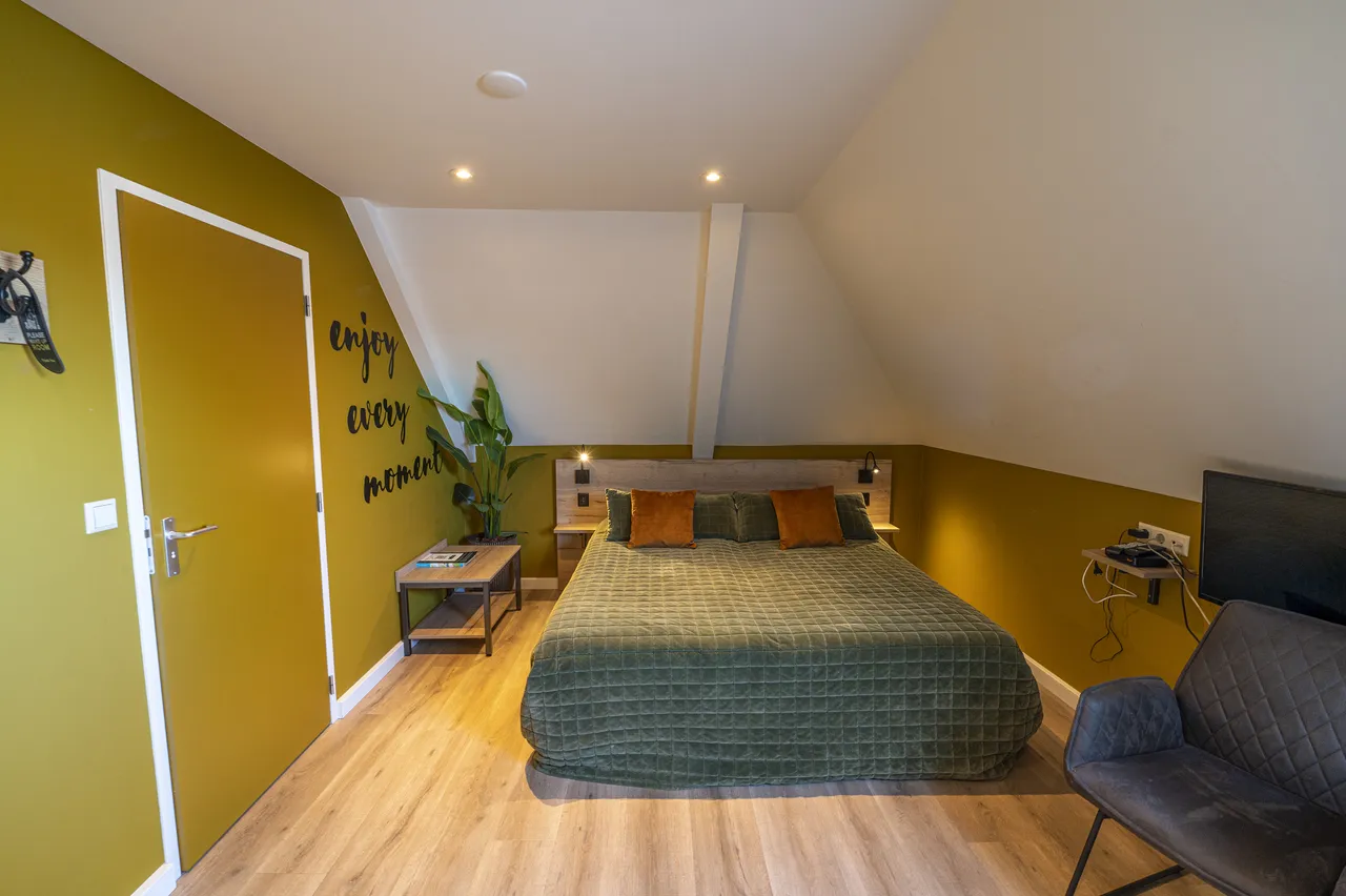 Boutique-kamer met okergele wand en de muurtekst enjoy every moment