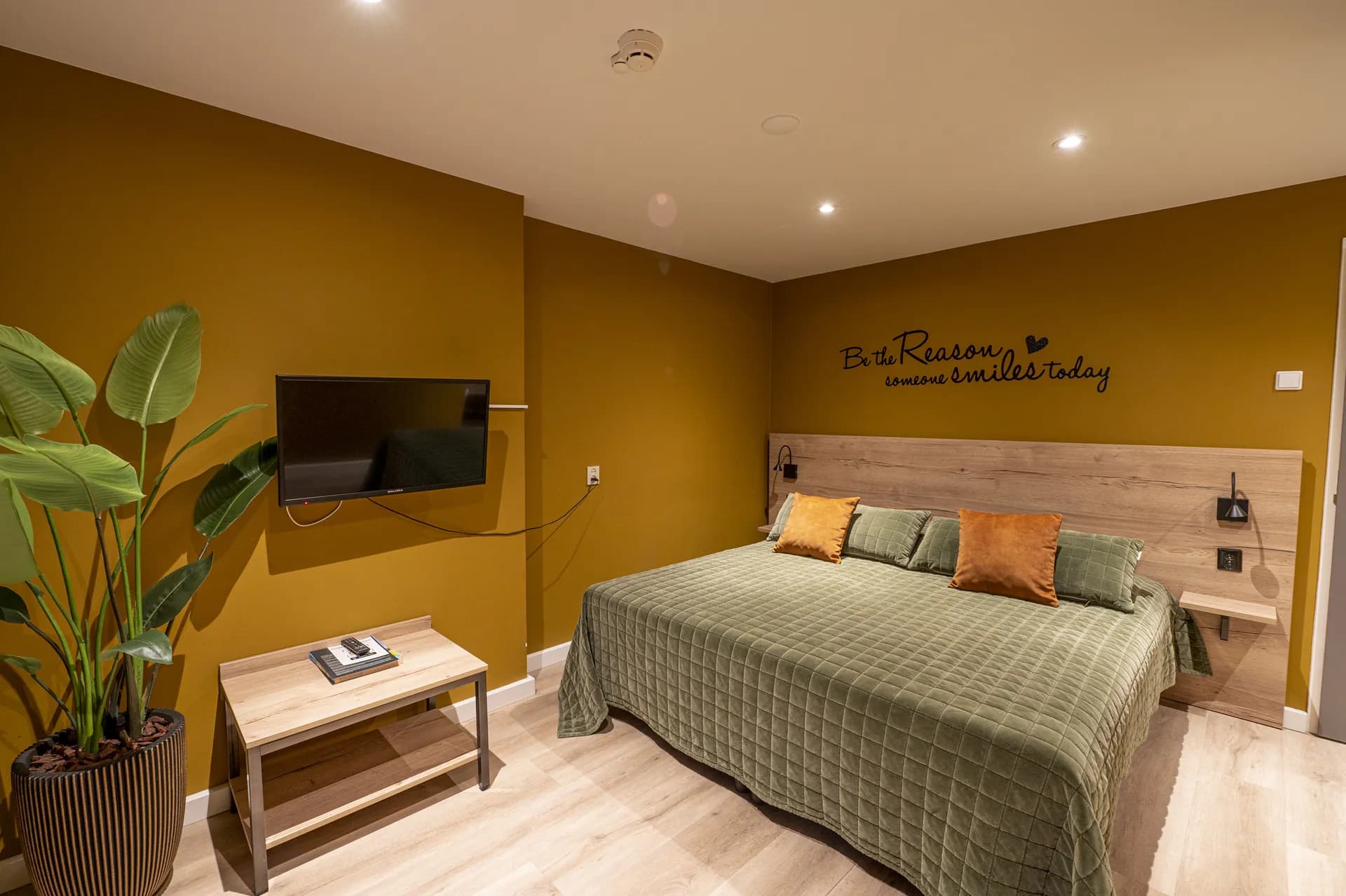 Hotelkamer met tweepersoonsbed en okergele wand