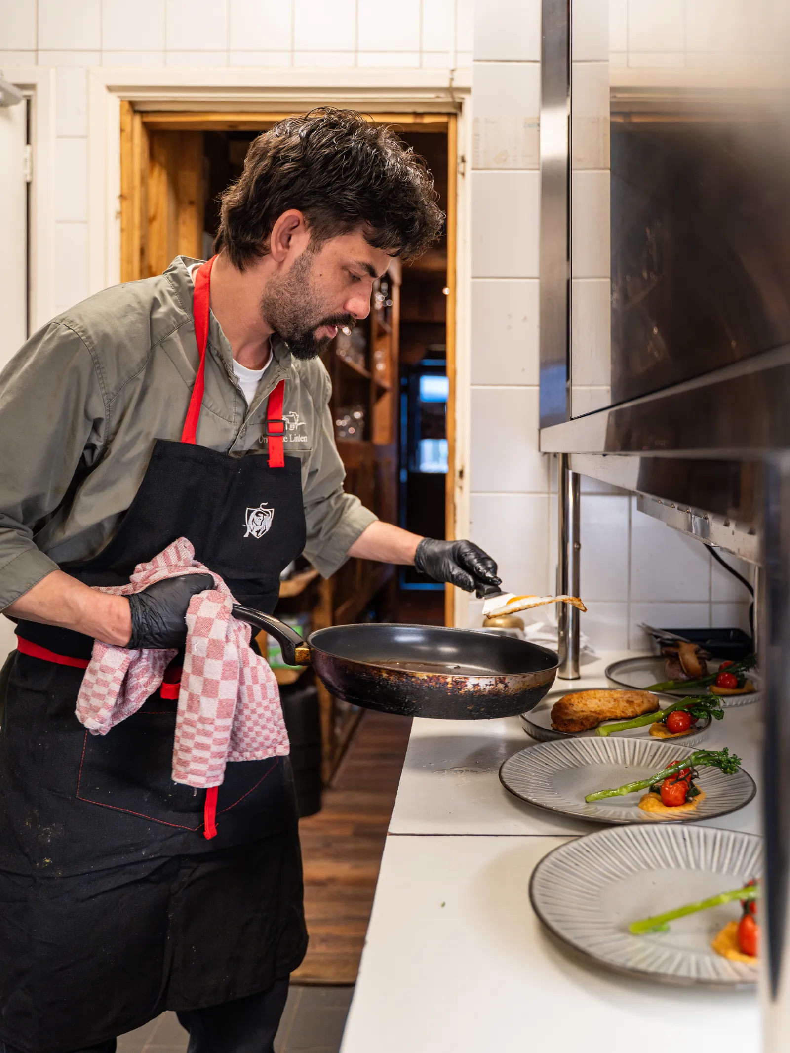Chef dresseert met aandacht borden aan de pass in de keuken