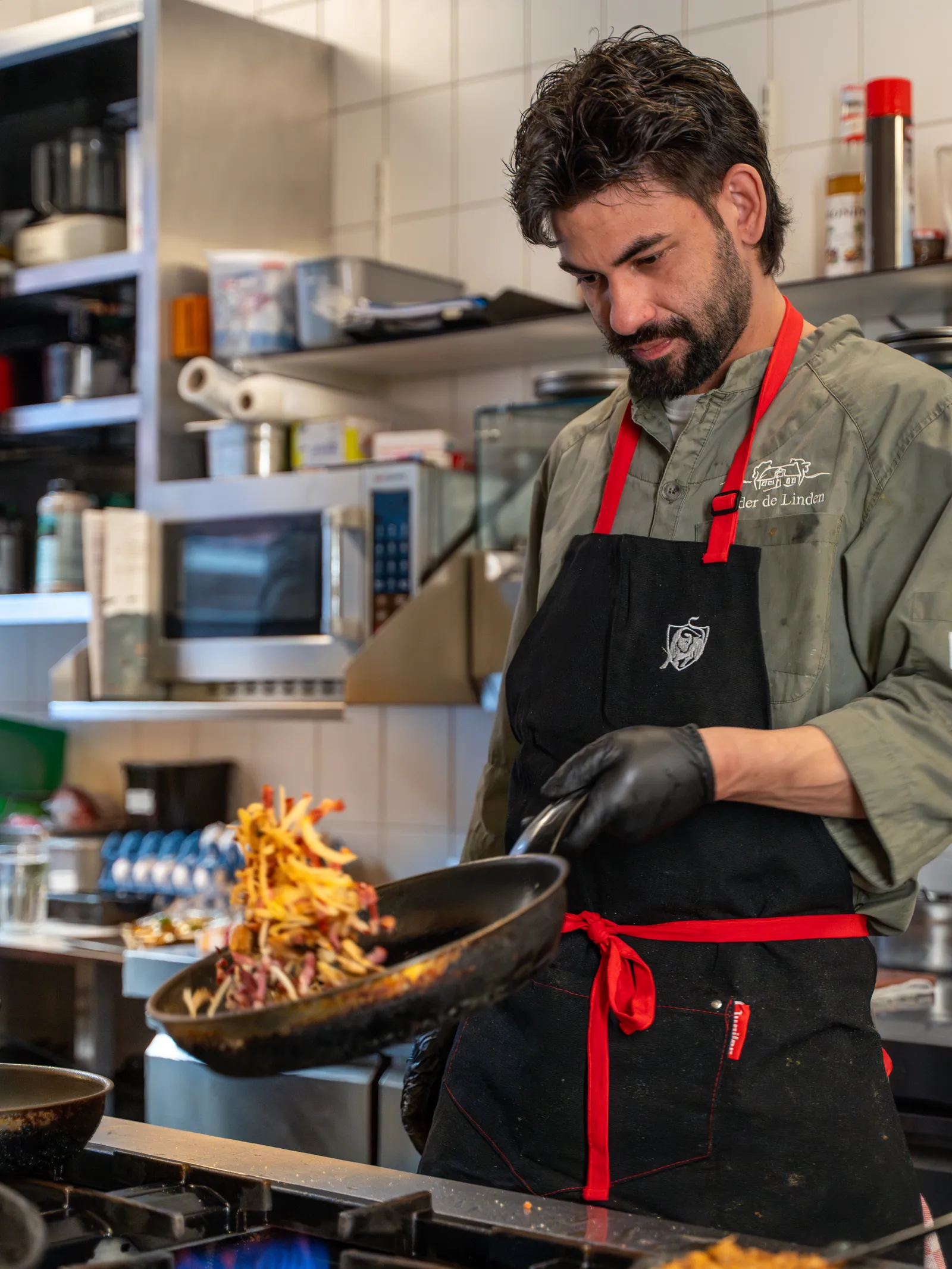 Kok schudt groenten en vlees op in een koekenpan in de keuken