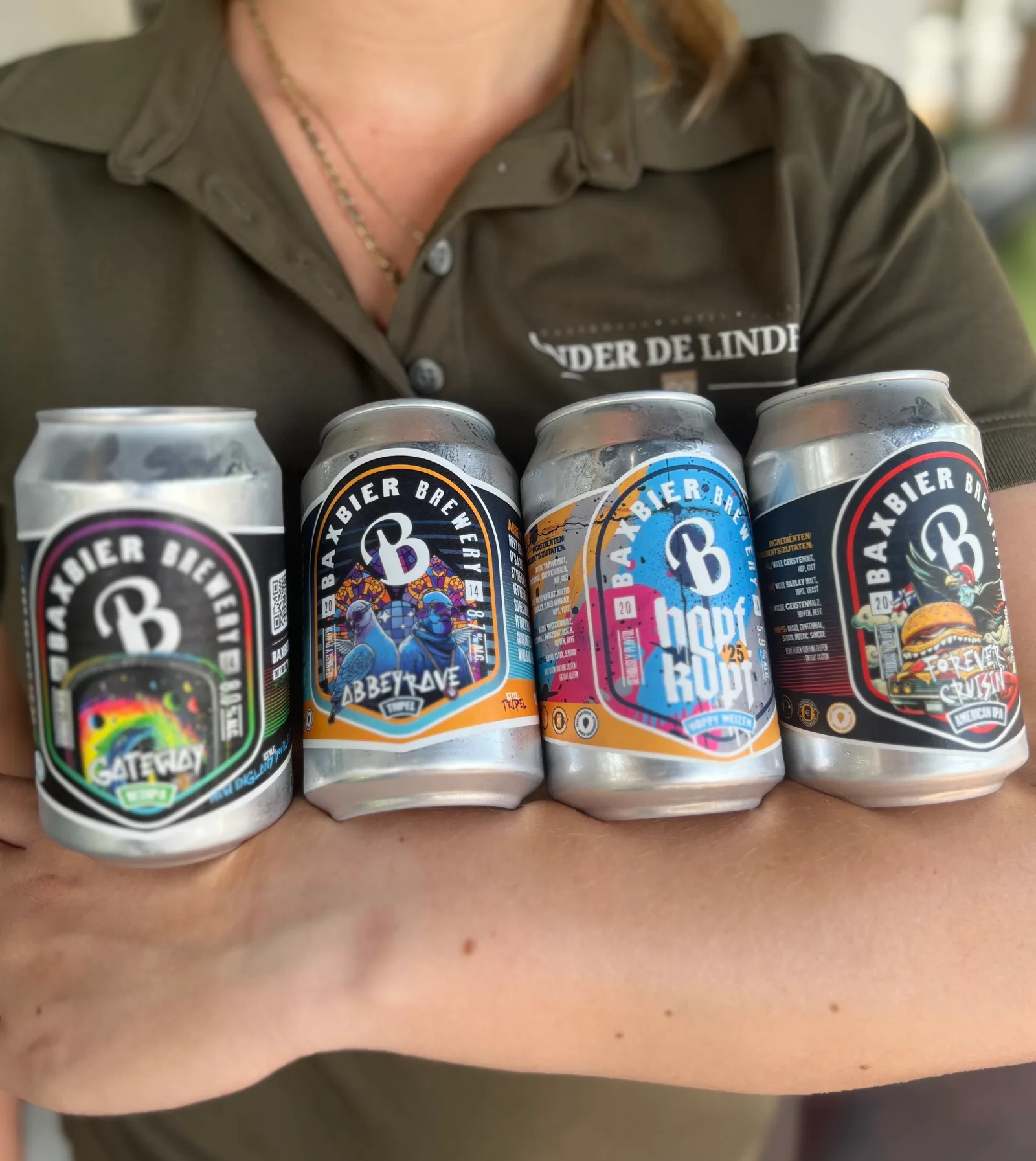 Collega houdt vier blikken speciaalbier van Baxbier Brewery op een rij tegen haar arm