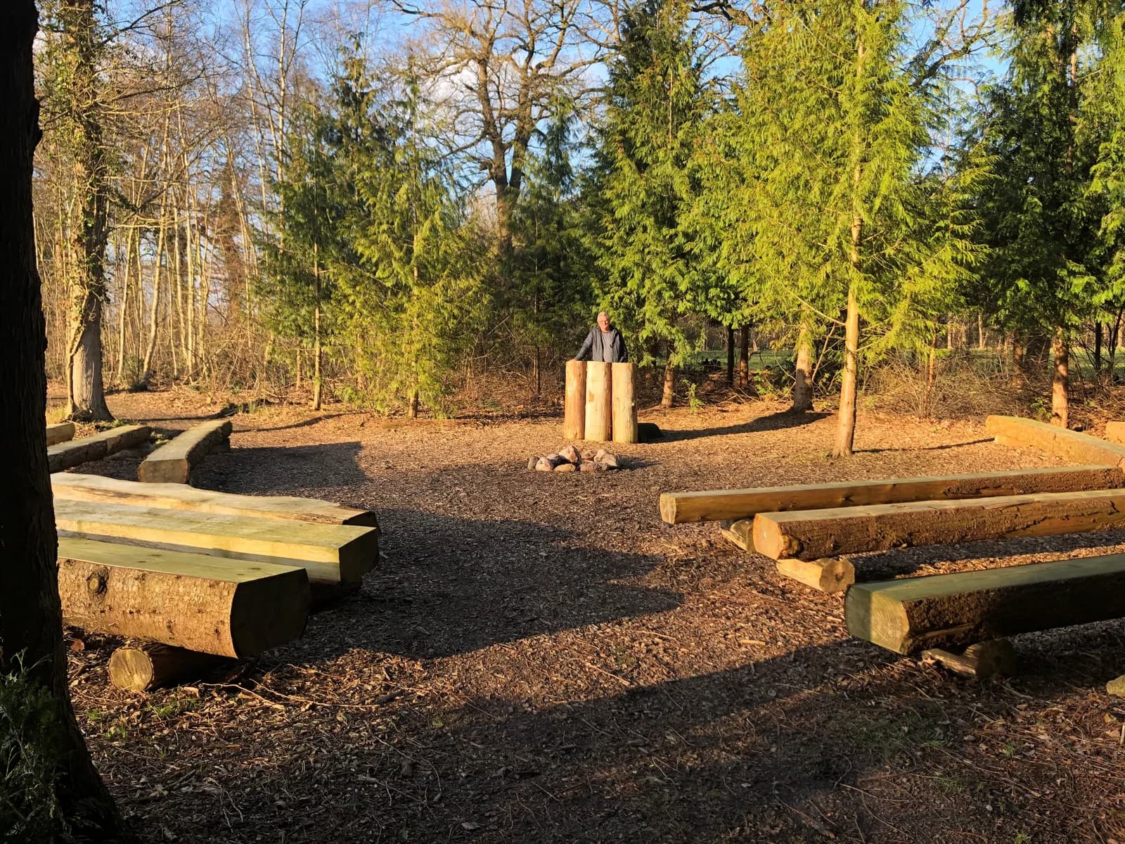Ceremonieplek in het bos bij Westervelde met houten banken rond een vuurplaats en een spreekgestoelte van boomstammen