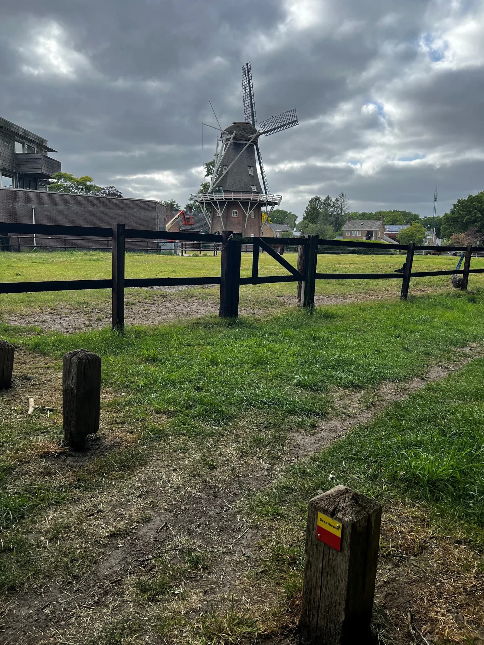 Korenmolen aan de rand van Norg, gezien over een weiland met een markeringspaaltje van het Drenthepad