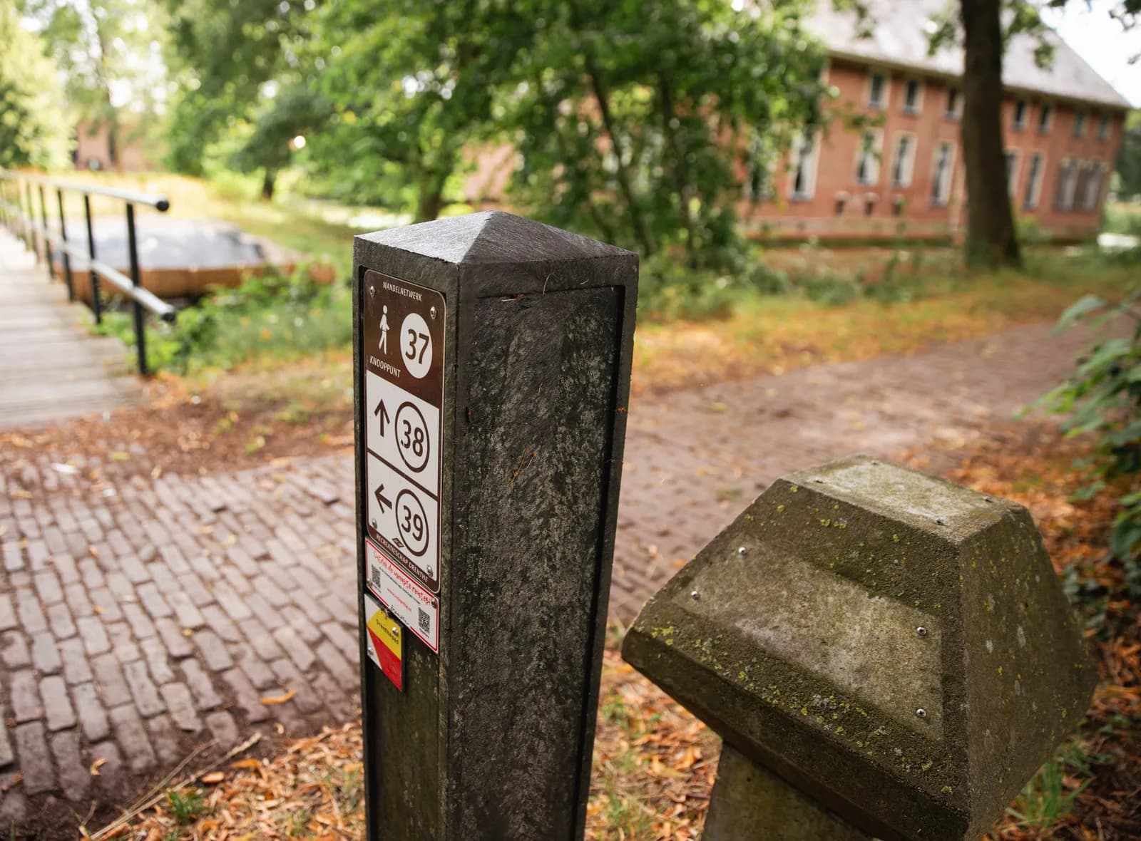 Wandelknooppuntpaal 37 met pijlen naar knooppunt 38 en 39, bij een brug over de gracht