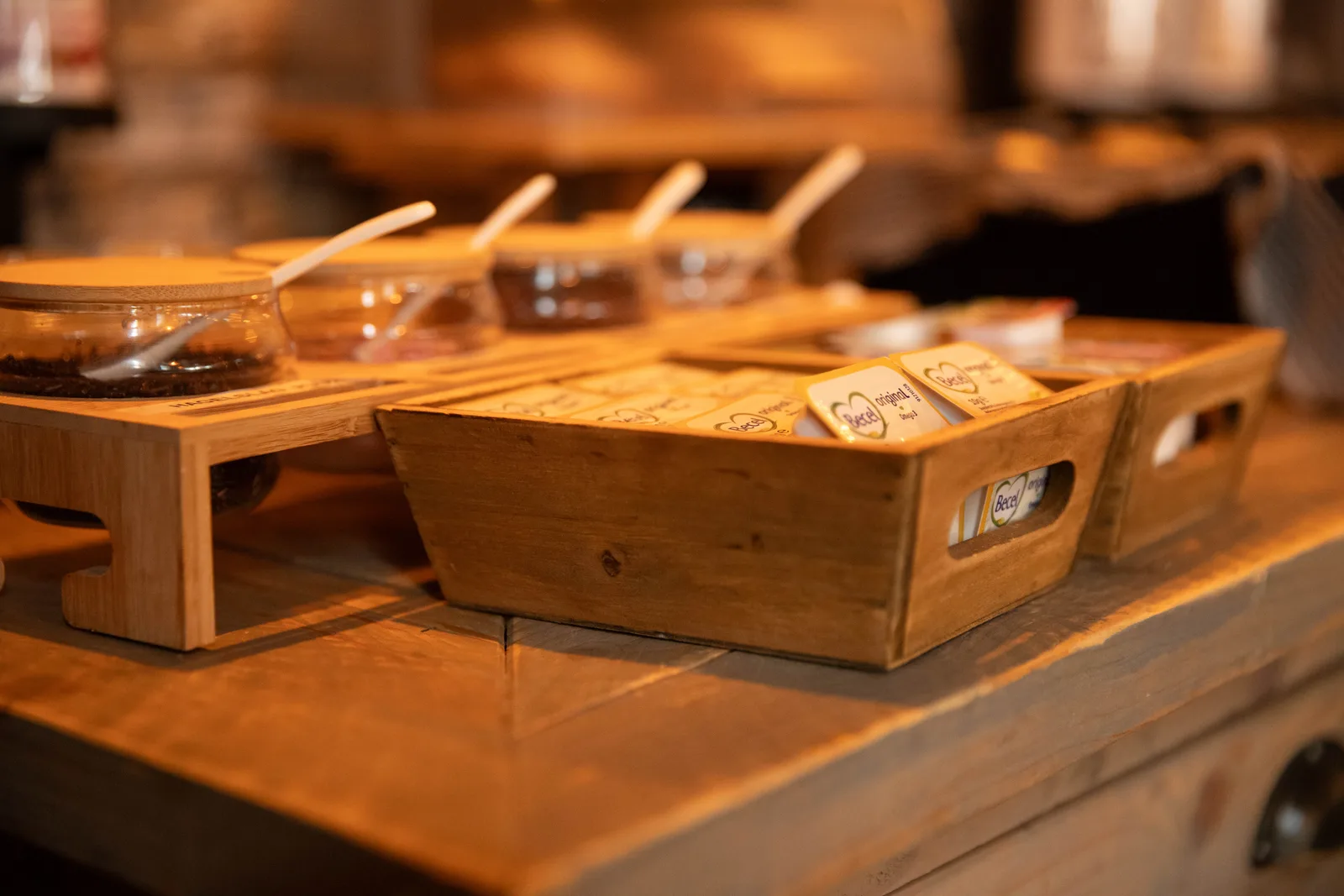 Houten kistjes met botercupjes en glazen potjes broodbeleg met lepeltjes