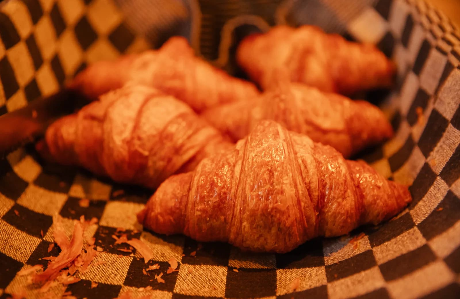 Verse croissants in een mandje met een blauw-wit geblokte doek