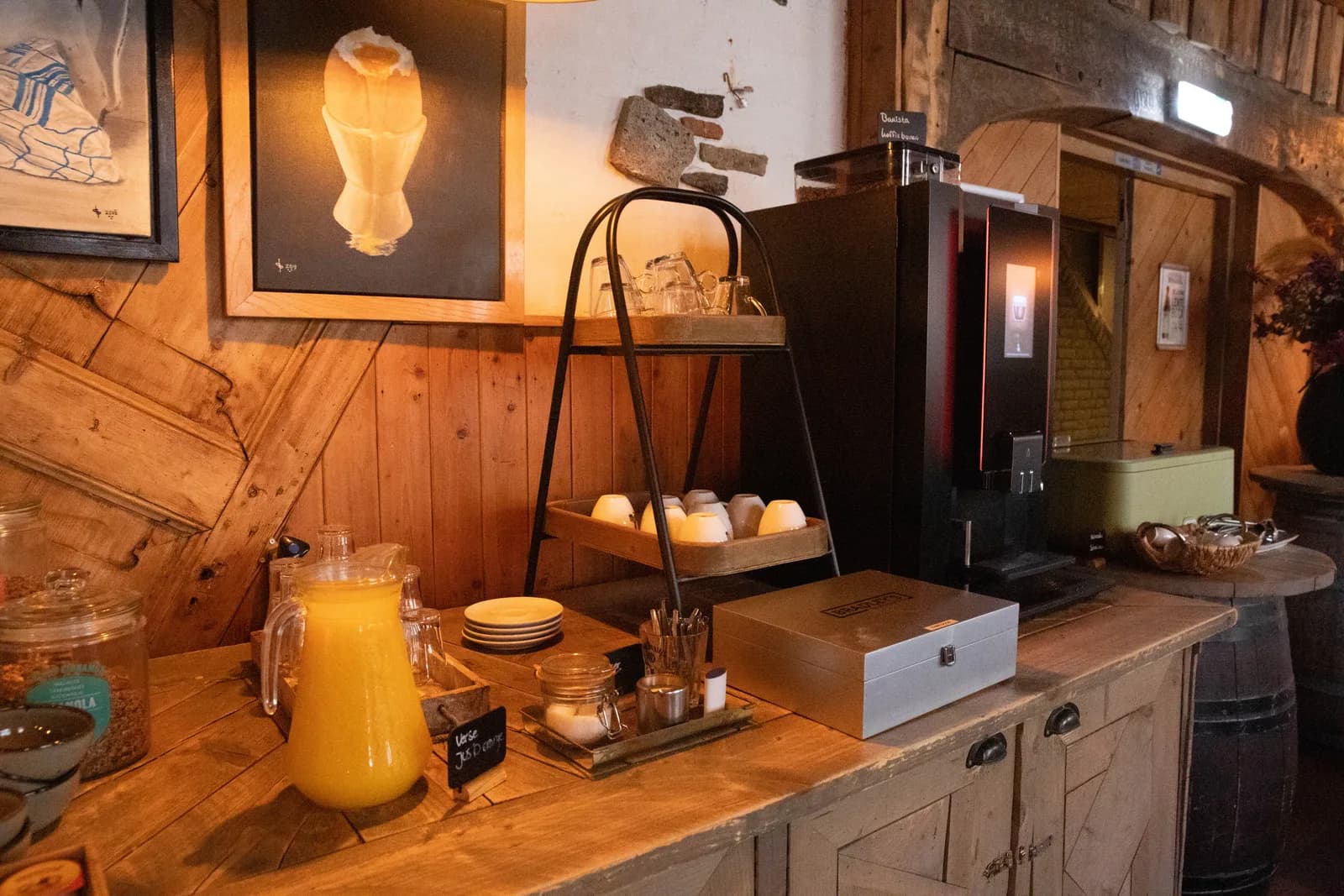Ontbijtbuffet tegen de houten wand met kan jus, kopjes, theekist en de koffiemachine
