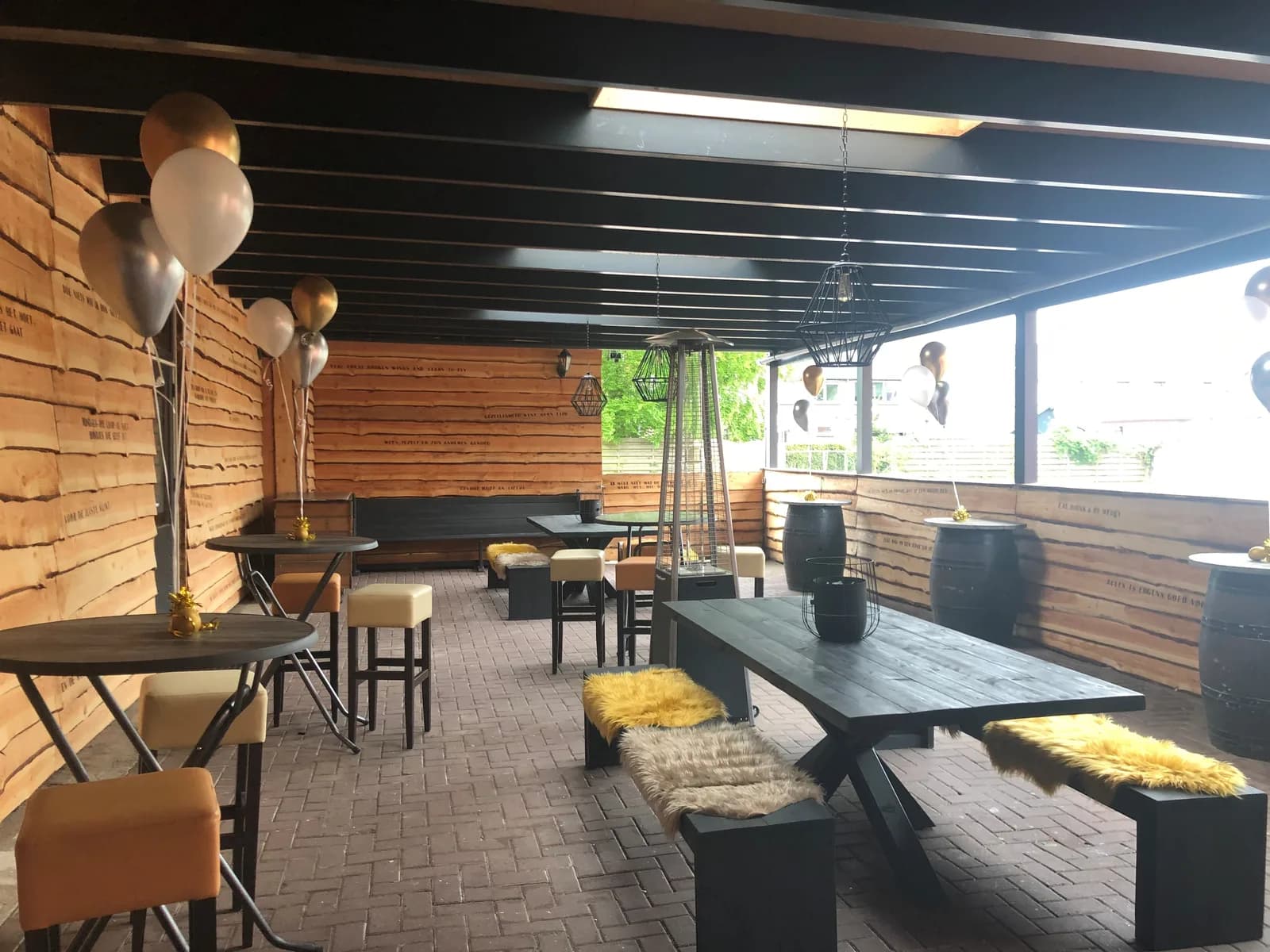 Overdekt terras met statafels en feestelijke ballonnen