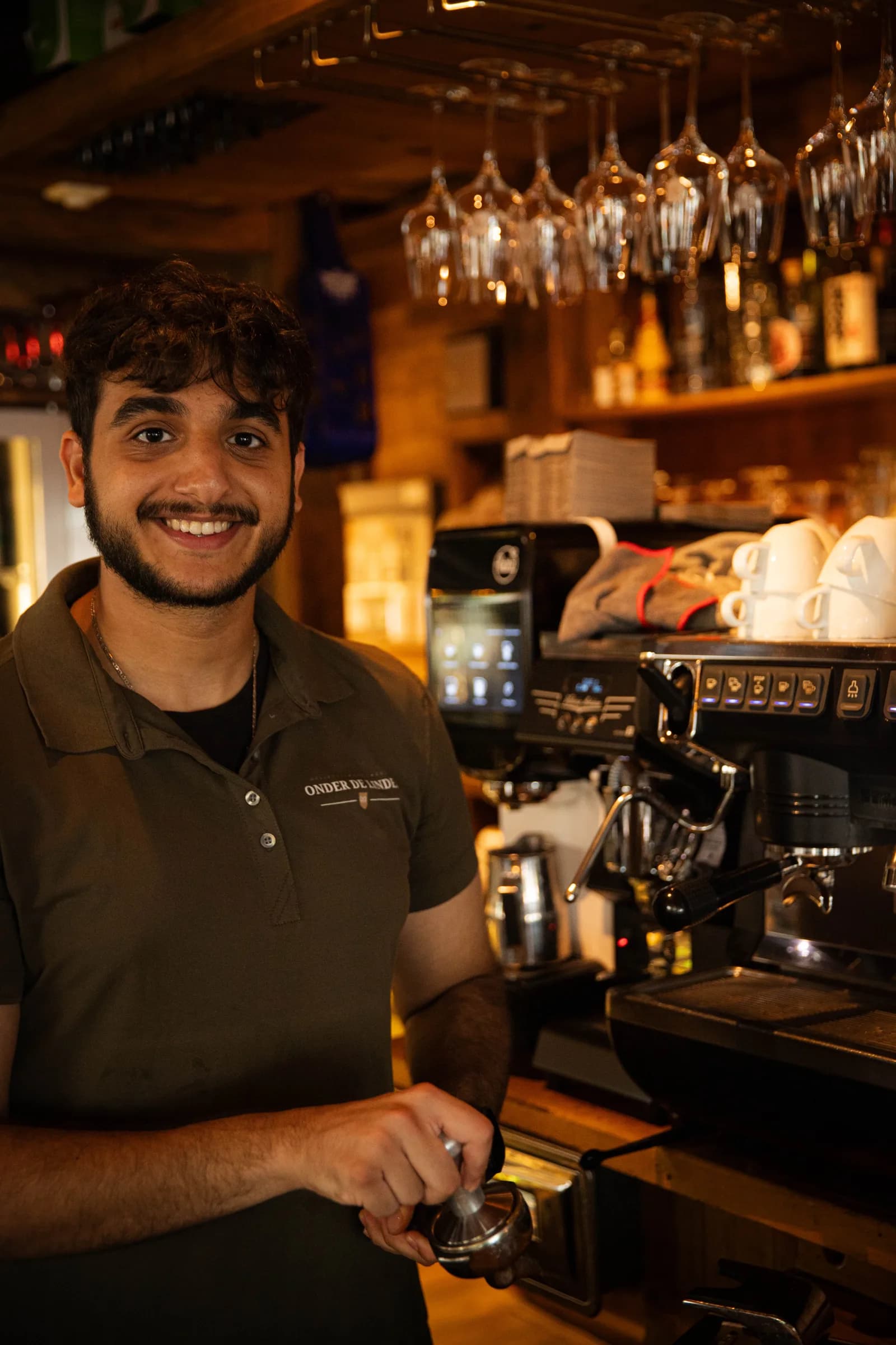 Lachende collega houdt de filterdrager vast bij de espressomachine achter de bar