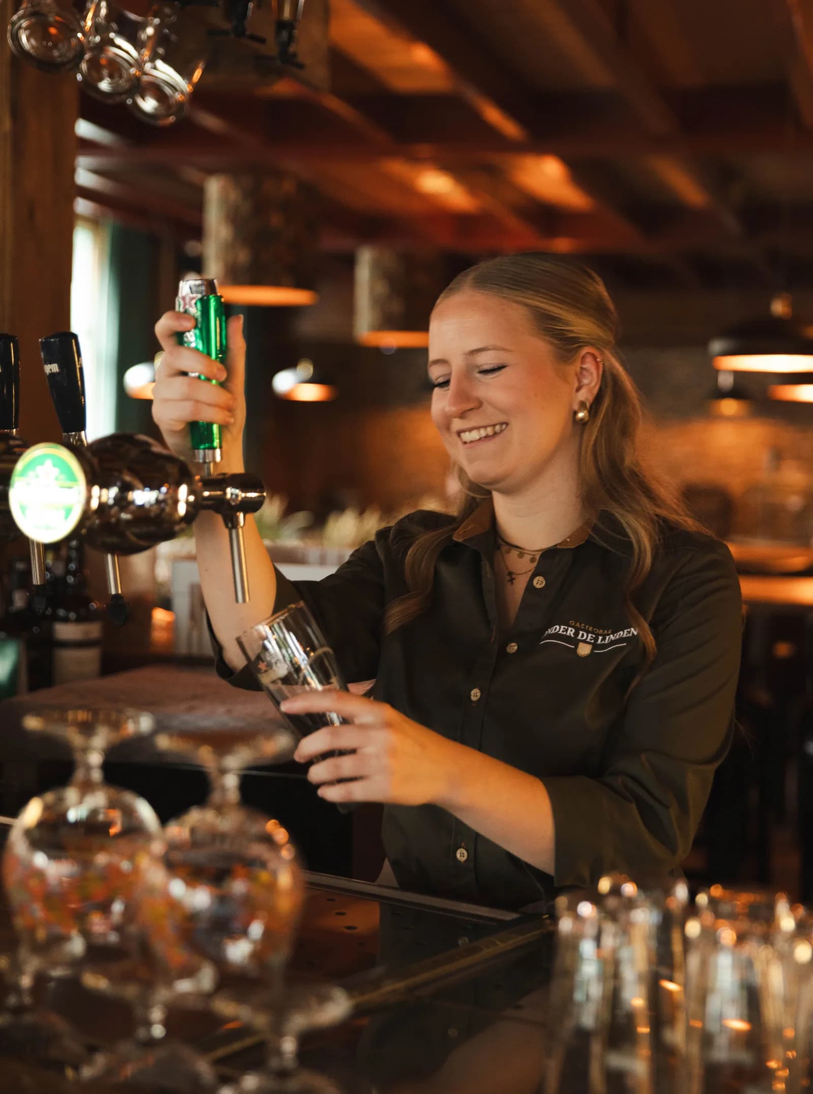 Lachende collega tapt een biertje aan de bar met het glas schuin onder de tap