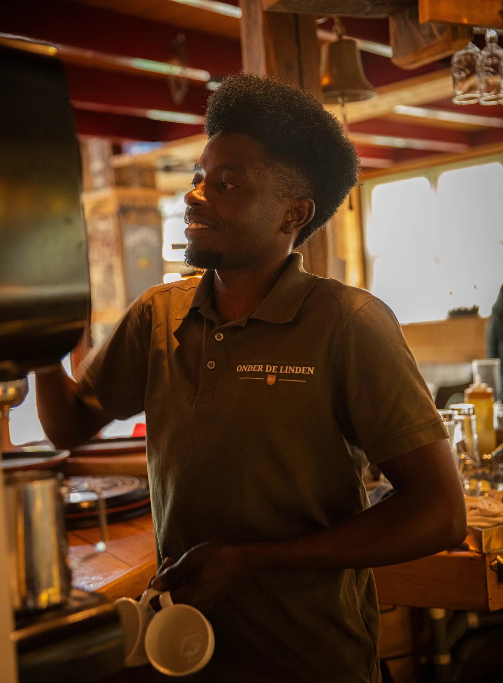 Collega met twee kopjes in de hand aan de koffiemachine achter de bar