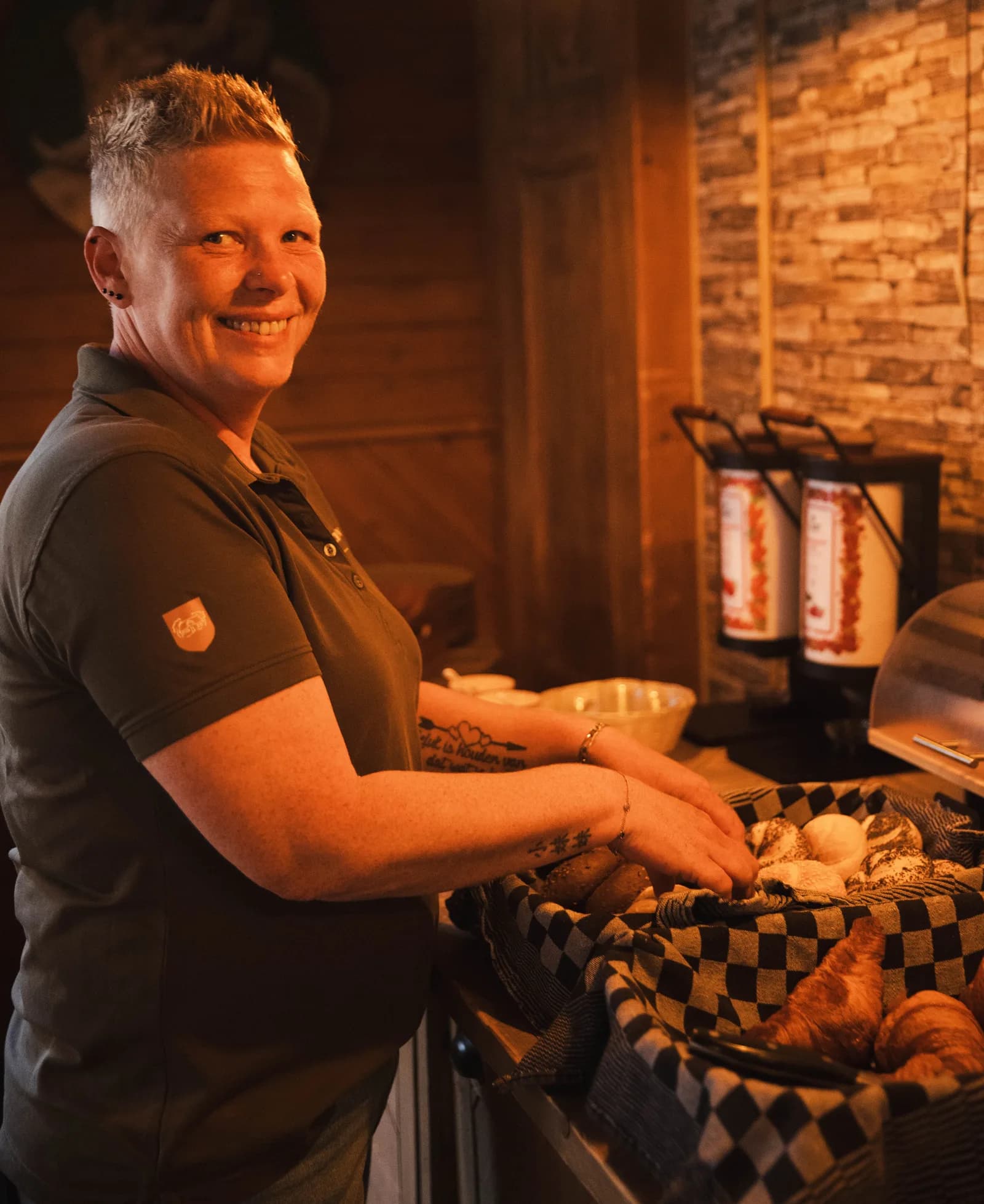 Medewerkster schikt de broodmand met geruite doek bij op het ontbijtbuffet