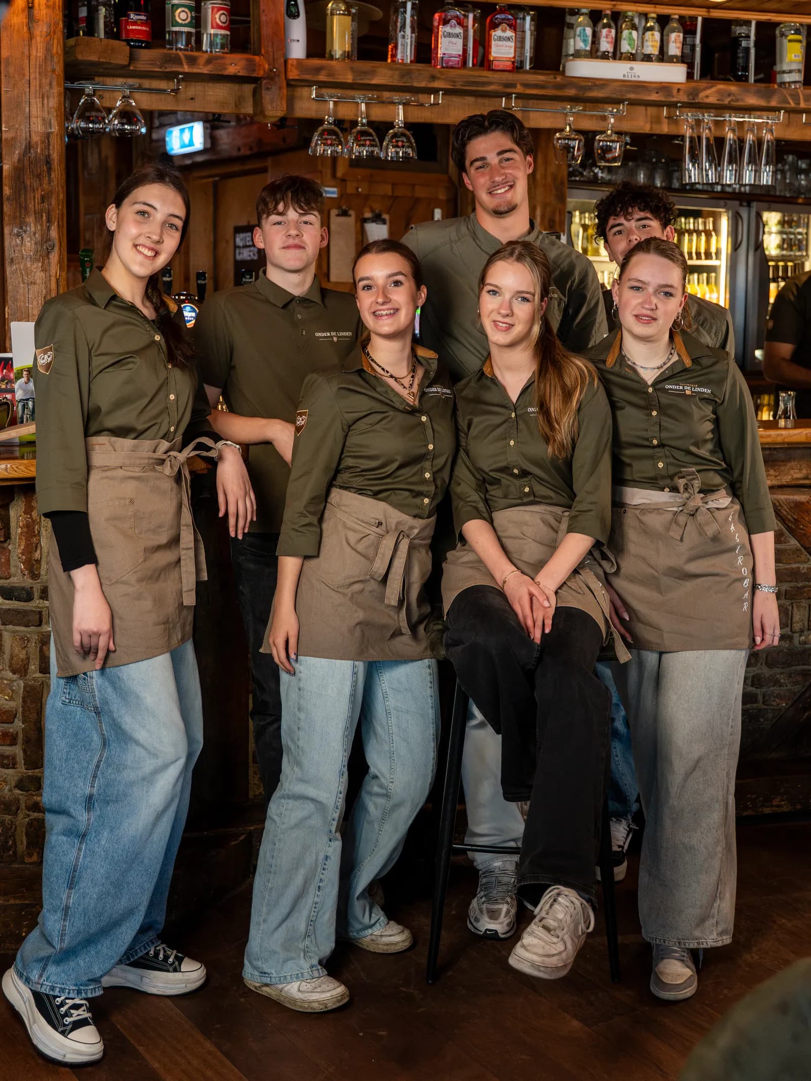 Het team van Onder de Linden in groene bedrijfskleding bij de bar