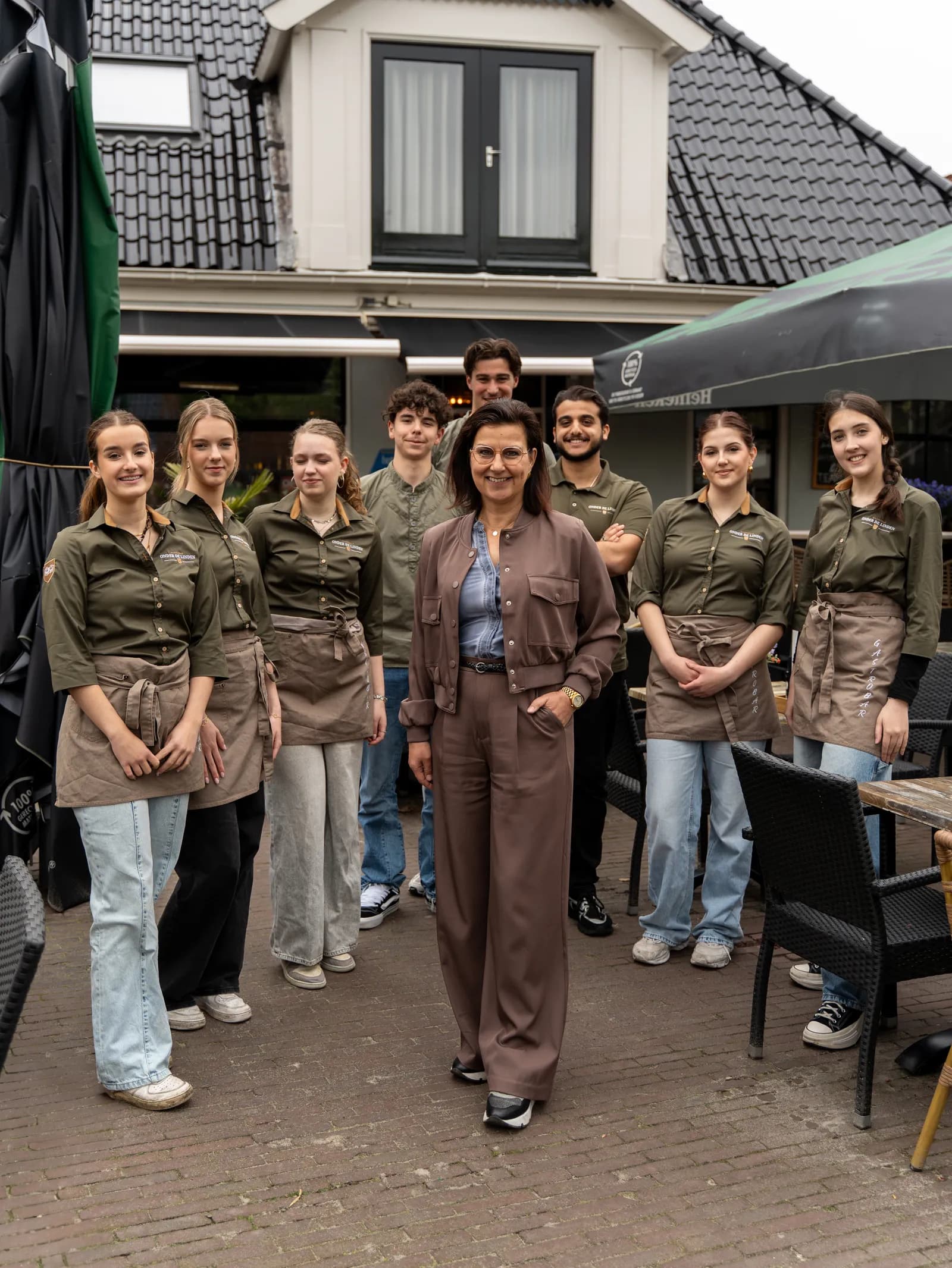 Het voltallige team met de eigenaresse vooraan op het terras voor het pand