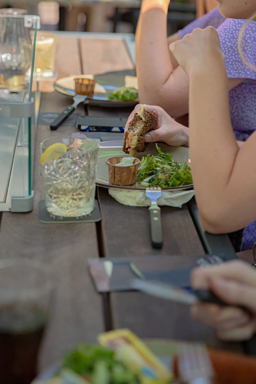Belegd broodje met salade en dipsaus aan een terrastafel