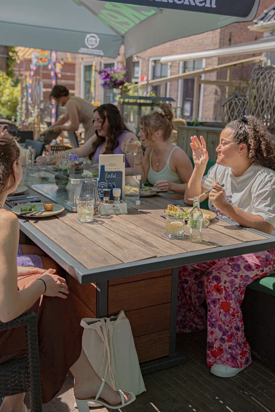 Gezelschap zit lachend aan een terrastafel in de zon