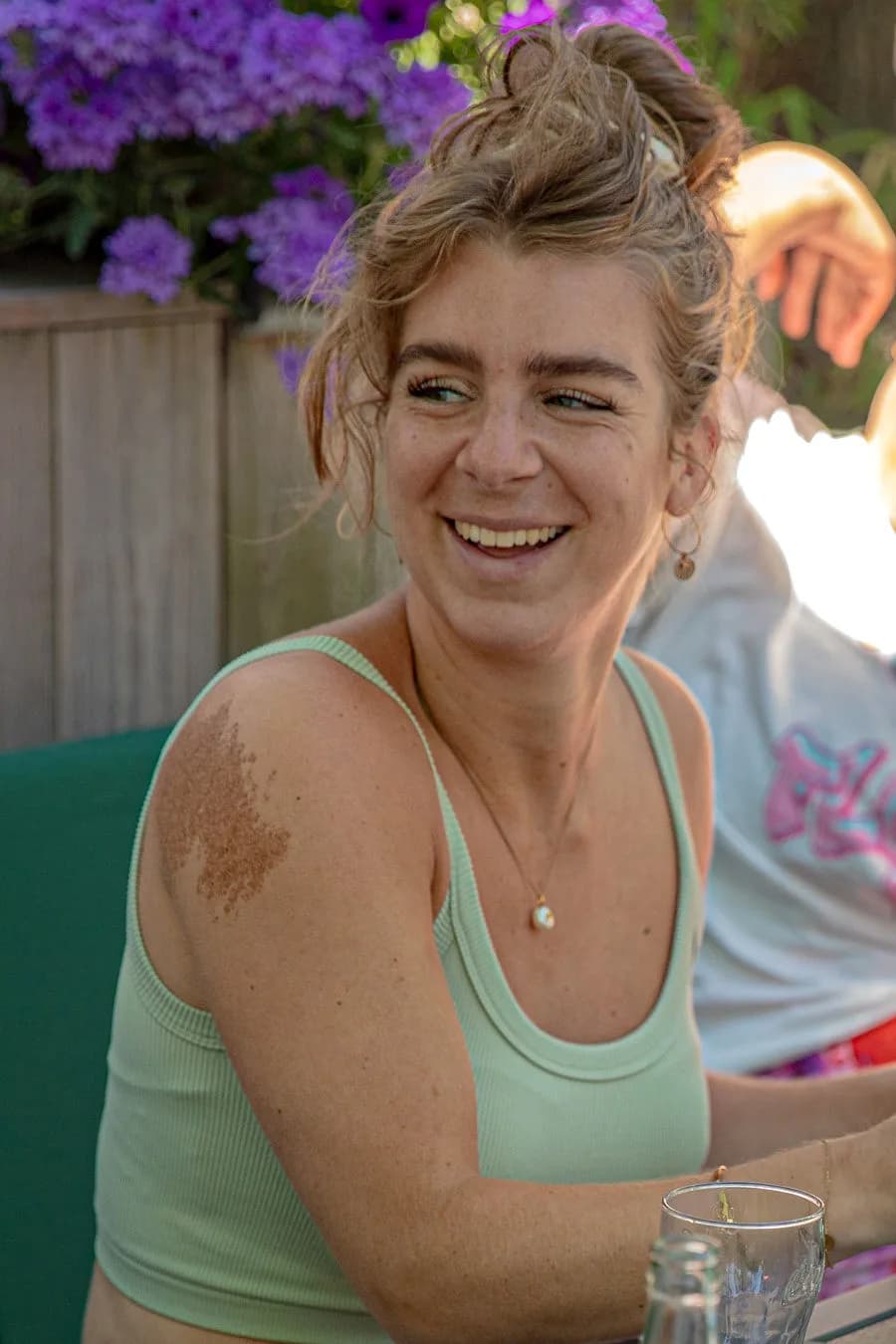 Lachende gast op het terras bij de hangbloemen