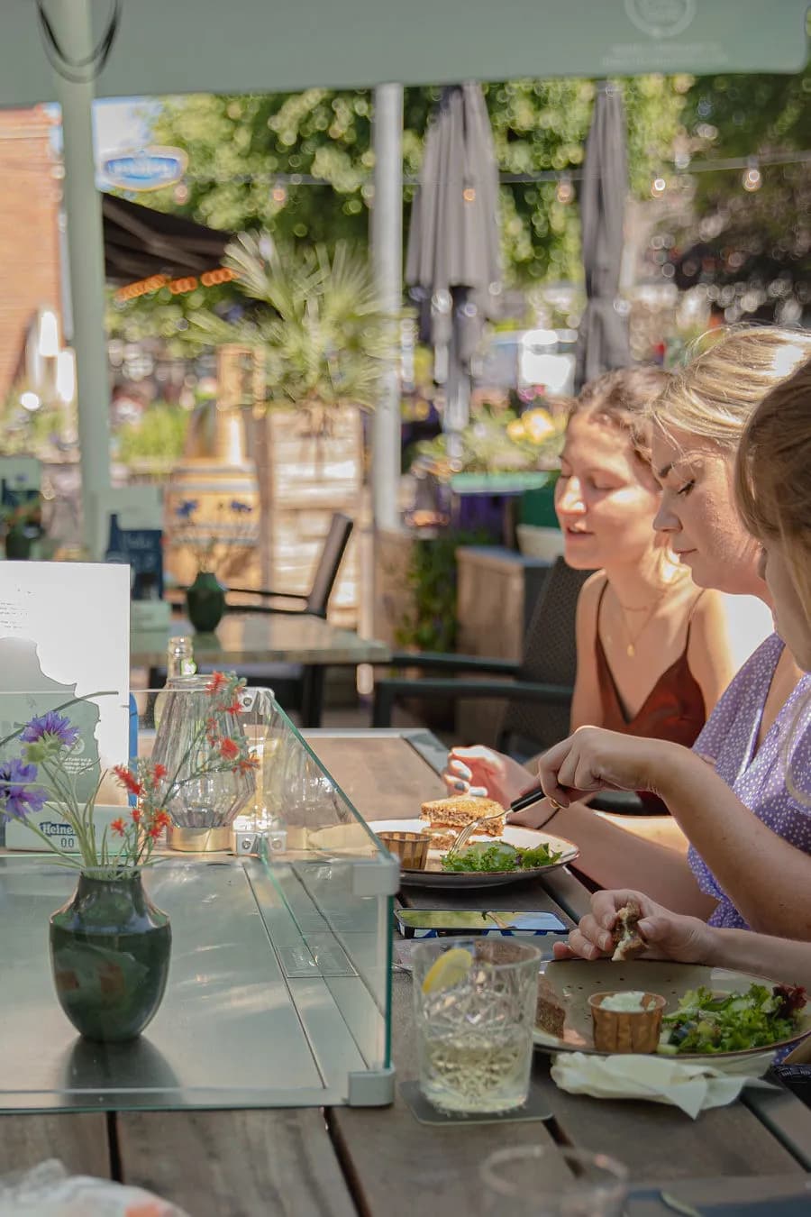 Gasten lunchen aan een tafel op het zonnige terras