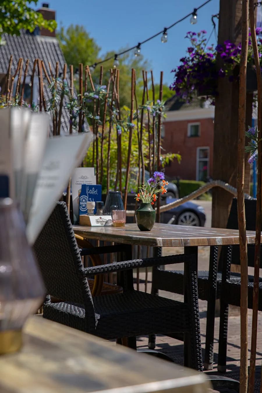 Terrastafel met bloemen en menukaartje in de zon