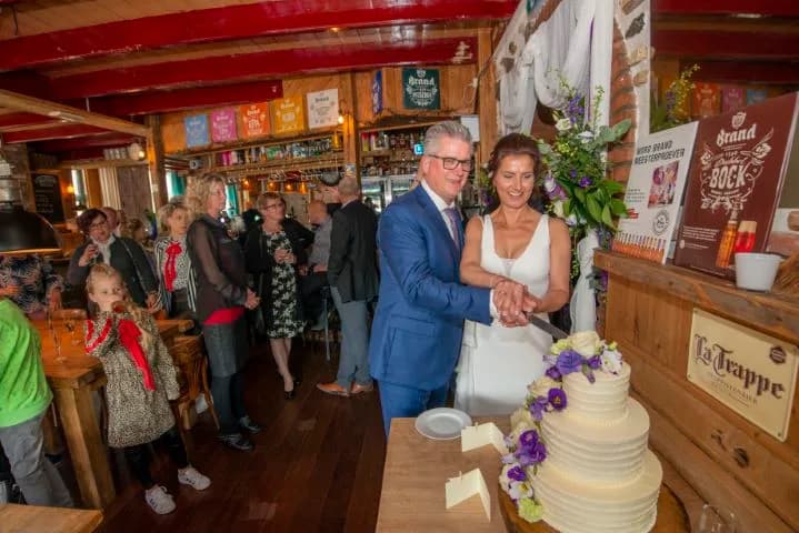 Bruidspaar snijdt de bruidstaart aan bij de bar