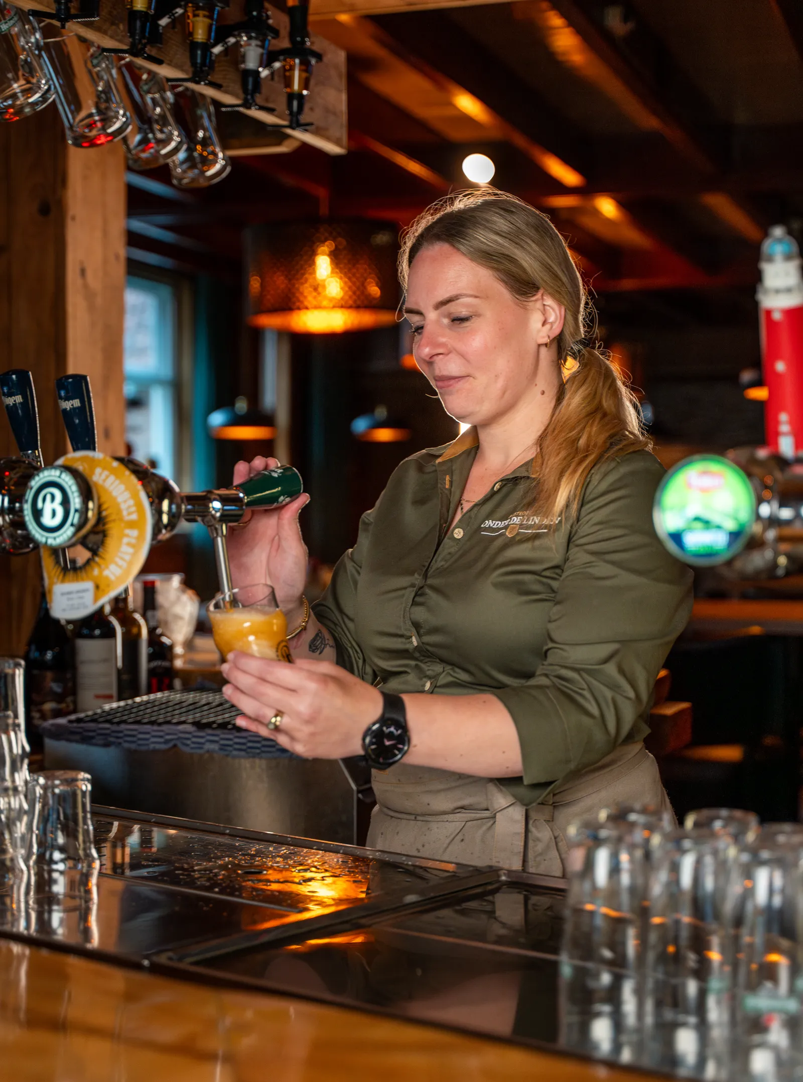 Medewerkster tapt een blond speciaalbier in een glas aan de bar