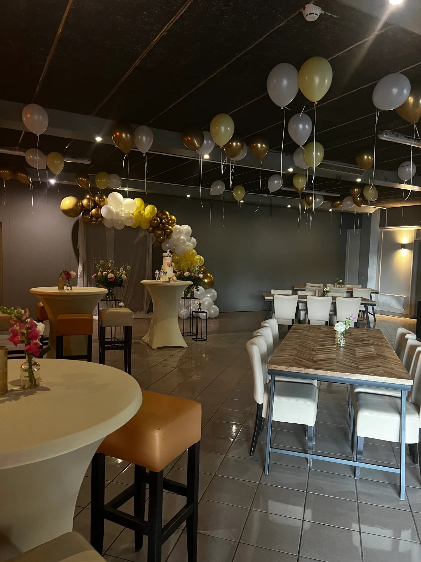 Statafels met bloemen en een lange gedekte tafel met witte stoelen